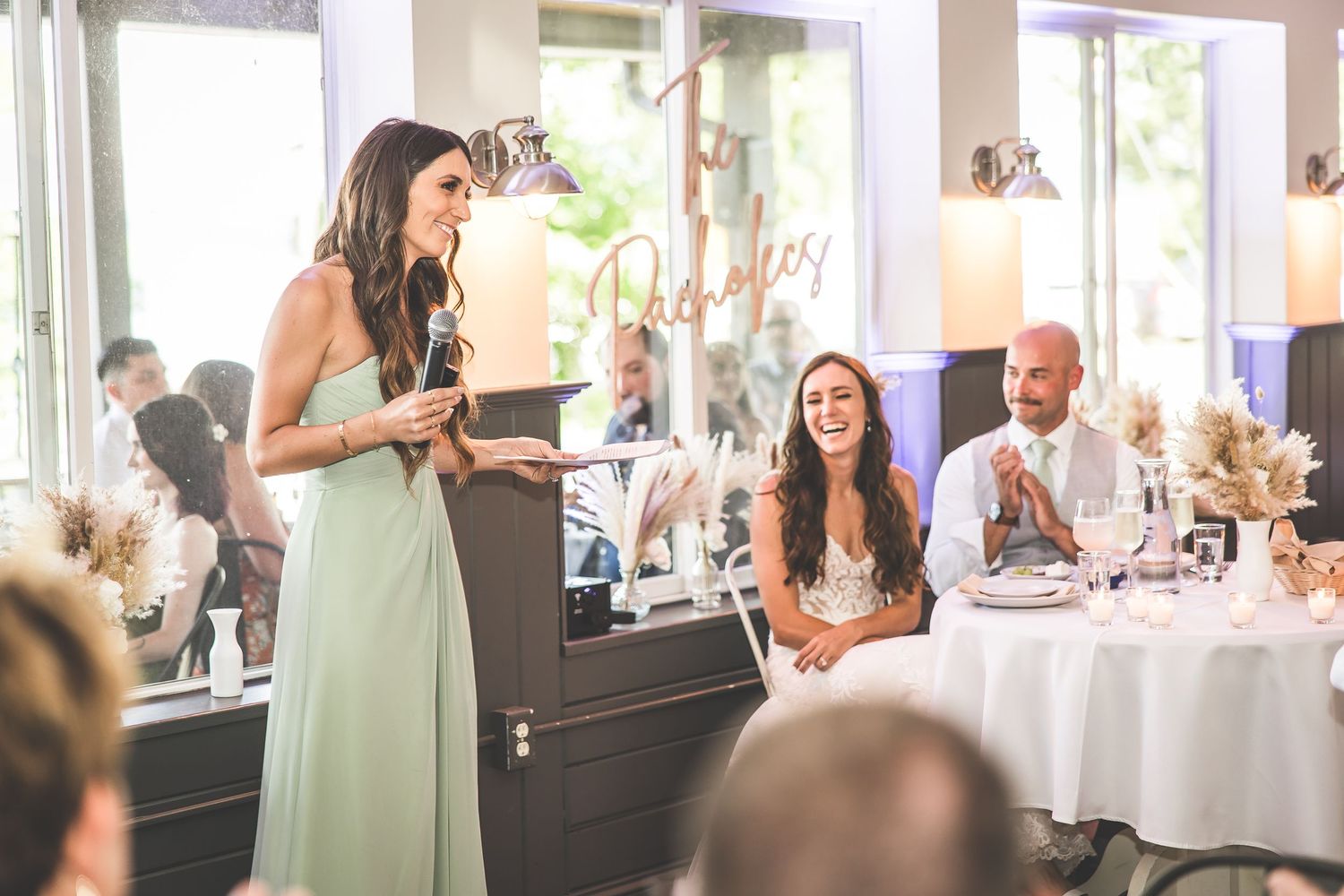 Bright reception venue with white columns and natural lighting streaming through windows.