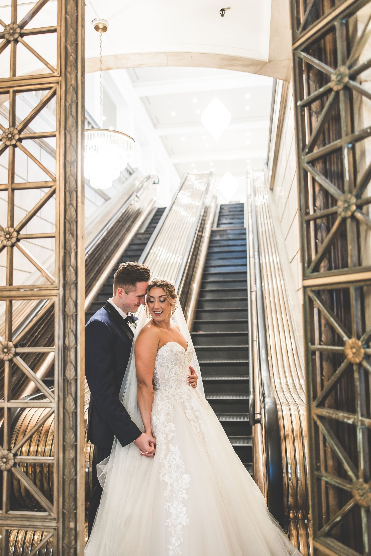 Romantic moment captured on vintage-style staircase with gold architectural elements.