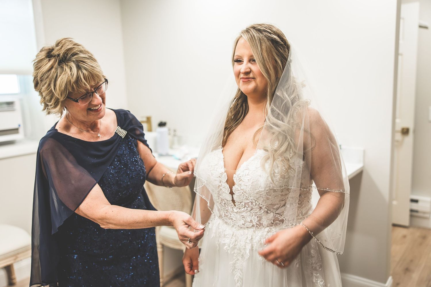 Final wedding dress preparations with helper making adjustments.