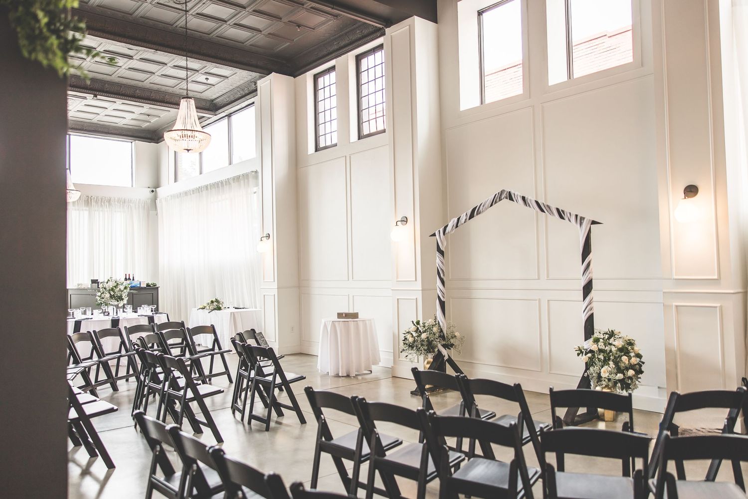 Large bright reception hall with rows of black chairs and white walls.