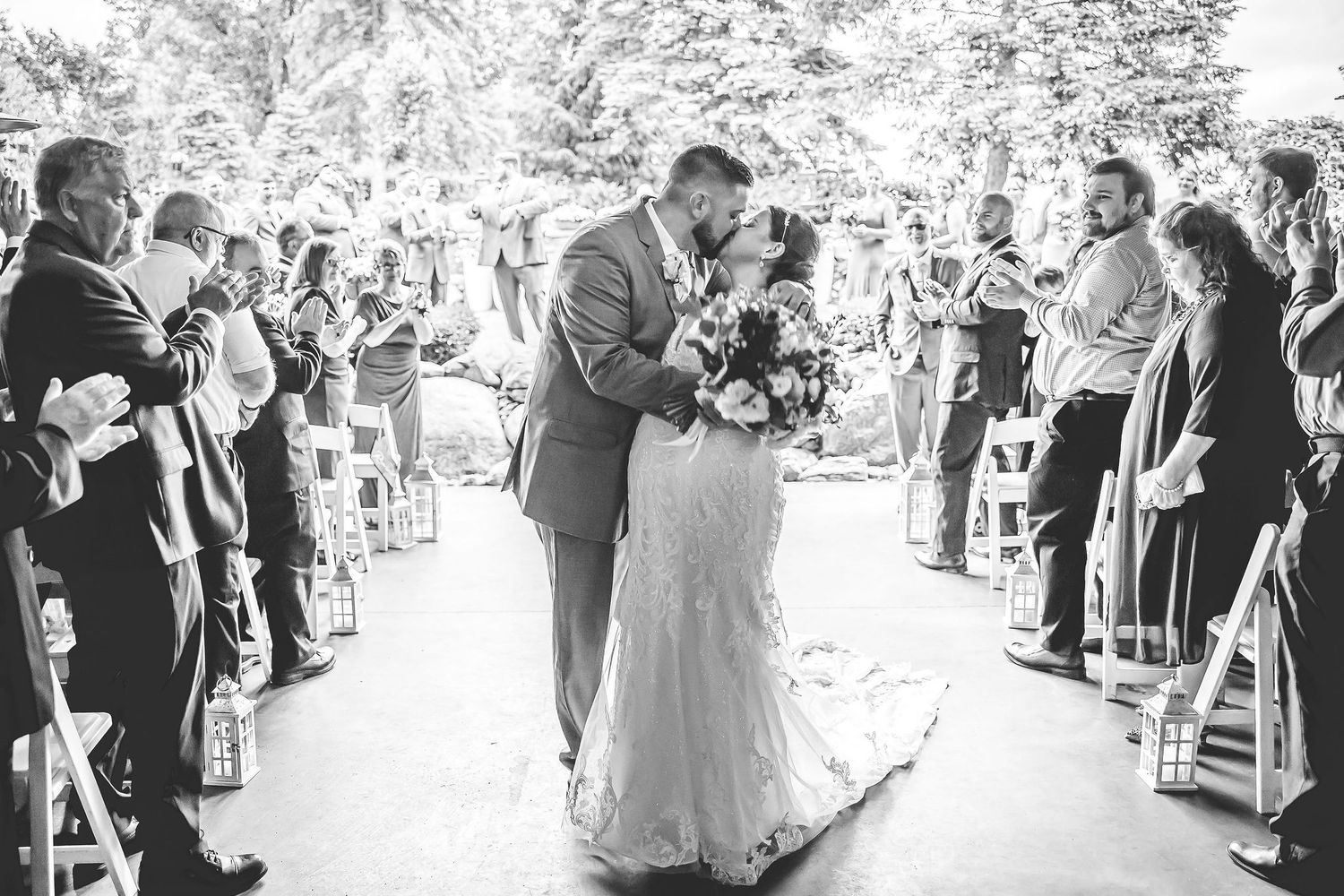 Wedding celebration with guests gathered under covered outdoor venue in black and white.