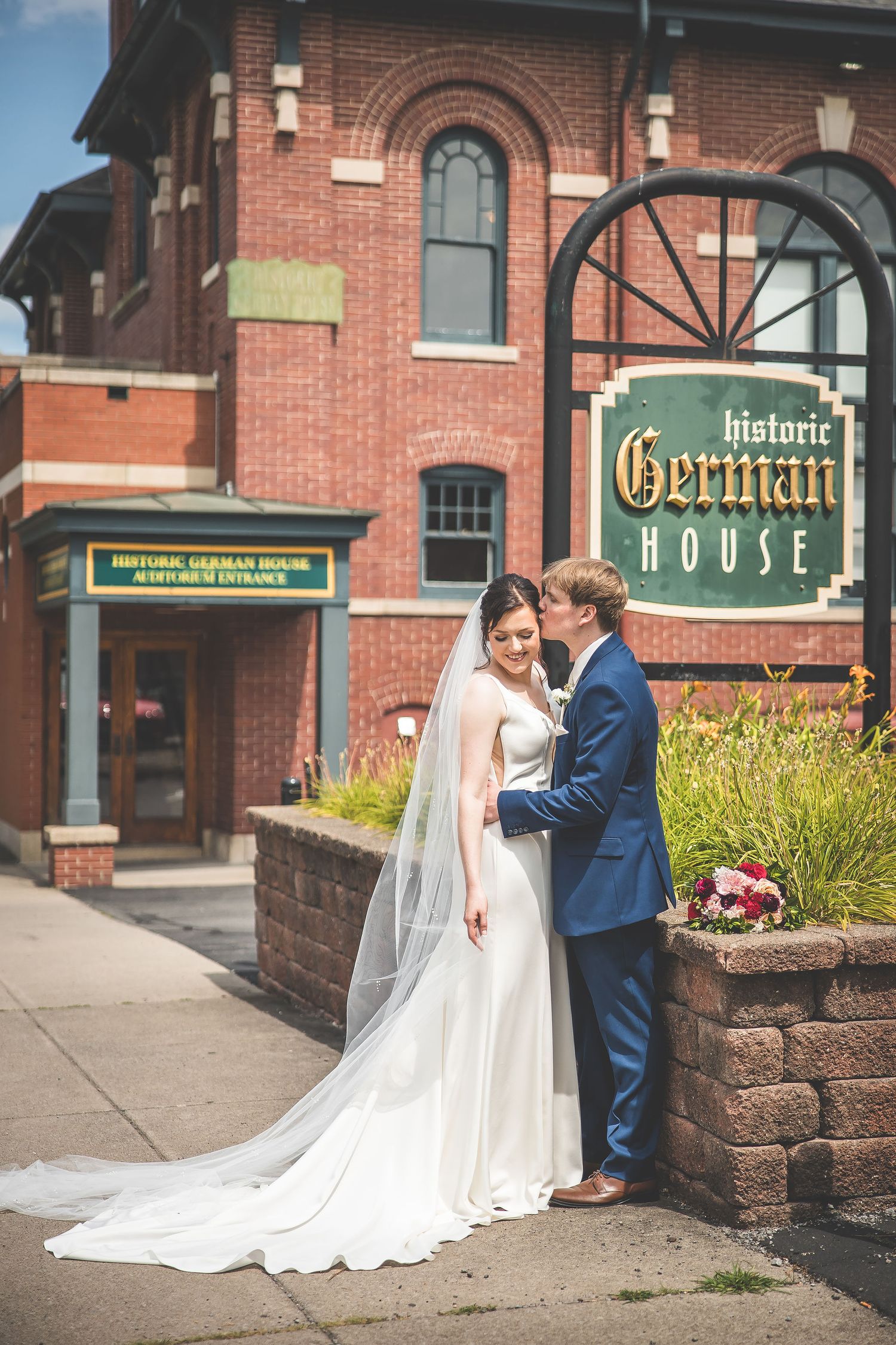Romantic wedding portraits captured in front of the German House's brick facade and signage.
