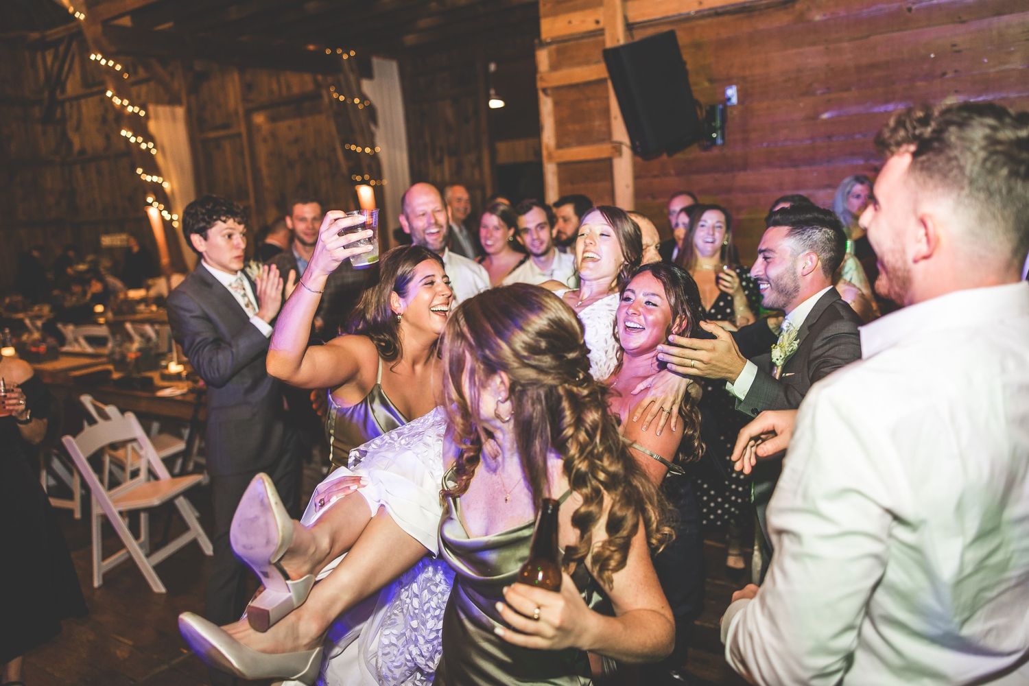 Wedding guests dancing enthusiastically on a crowded dance floor at a reception party.