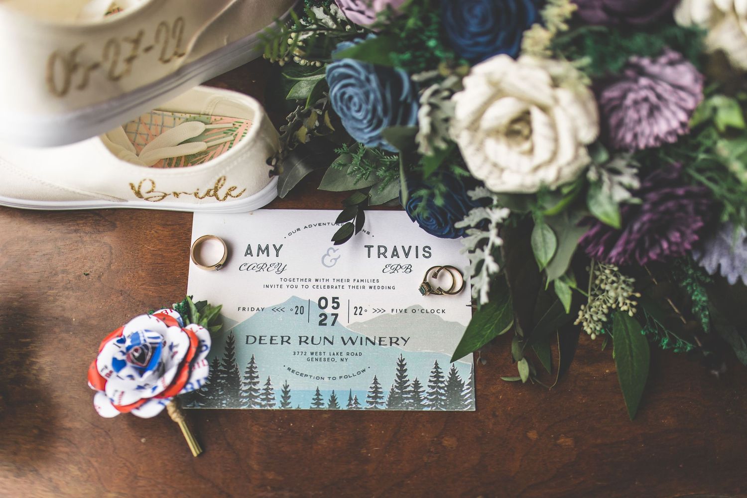Wedding invitation and floral decorations arranged on wooden surface.
