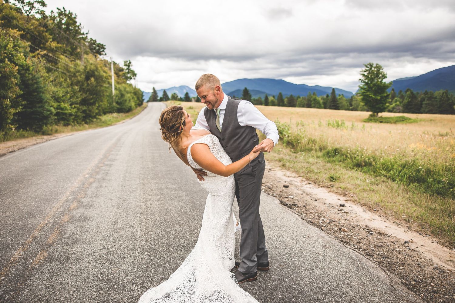A romantic wedding photo session on a winding country road with mountain views.