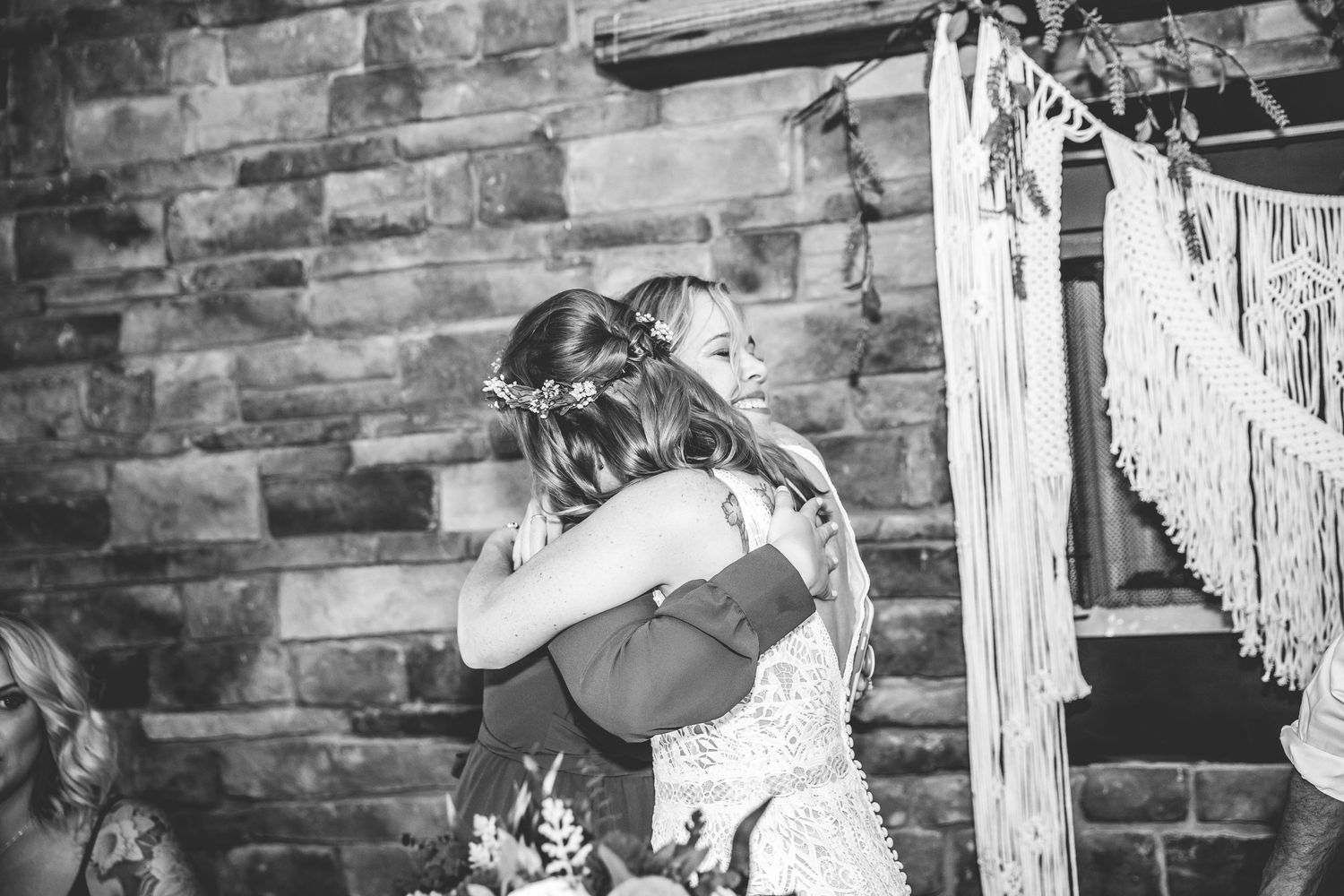 Black and white photo of a rustic wedding venue with exposed brick walls and wooden beams.
