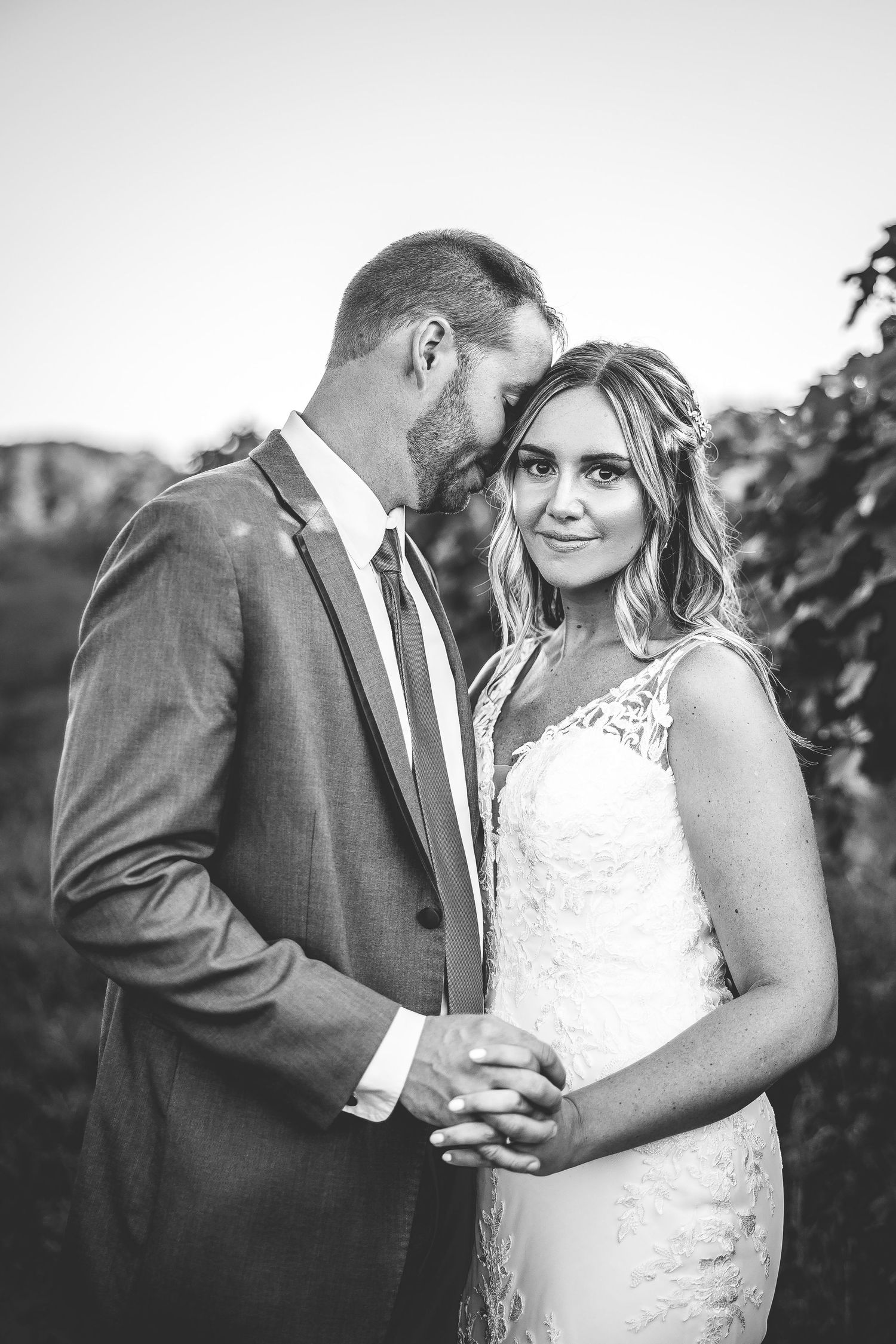 A romantic moment between newlyweds sharing an intimate embrace in a vineyard setting.