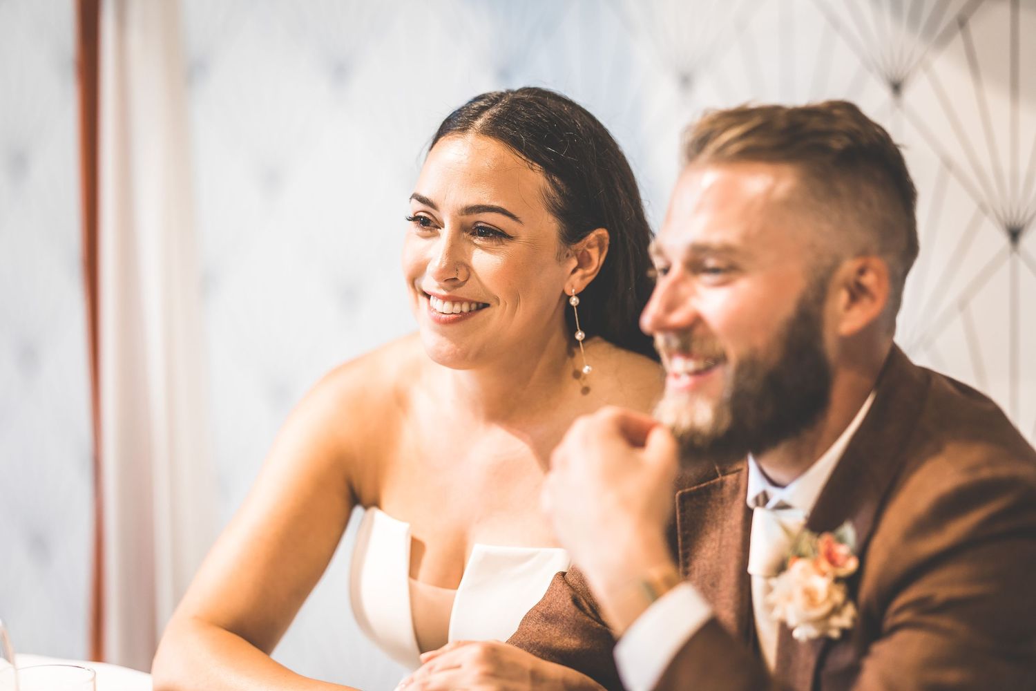 Candid moment during wedding reception with couple seated at decorated head table.