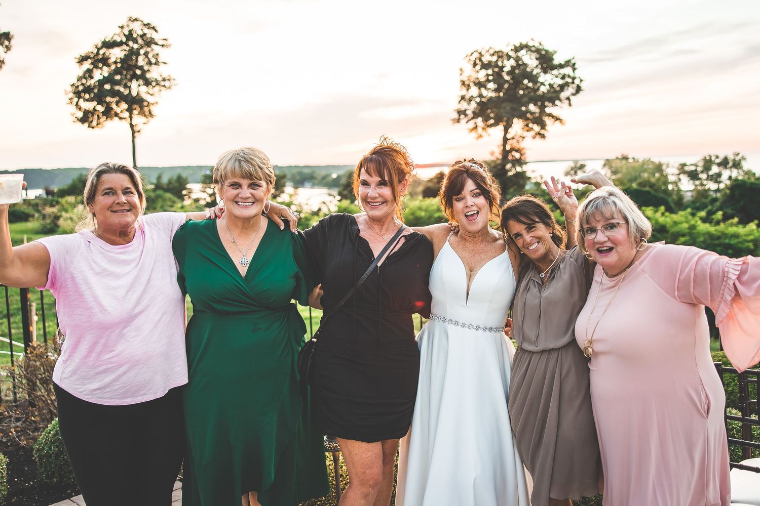 Wedding party group photo with bridesmaids wearing coordinated pastel and green dresses.