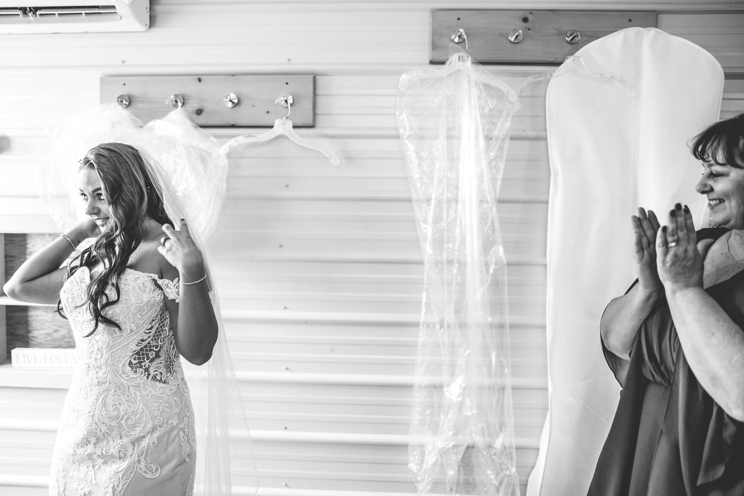 Wedding dress preparations with multiple gowns hanging in a bright room.
