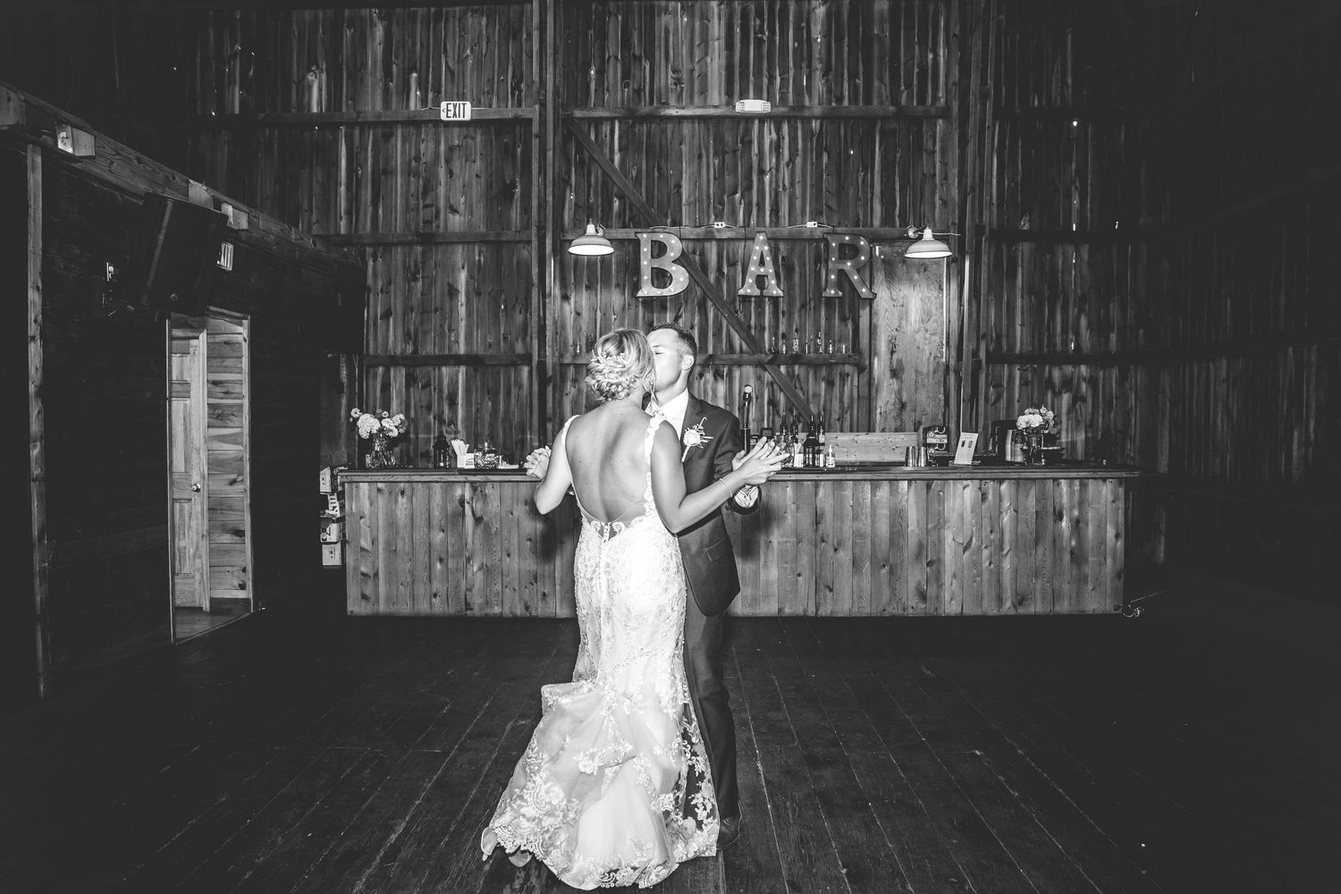A romantic first dance between newlyweds in a rustic barn venue with string lights overhead.