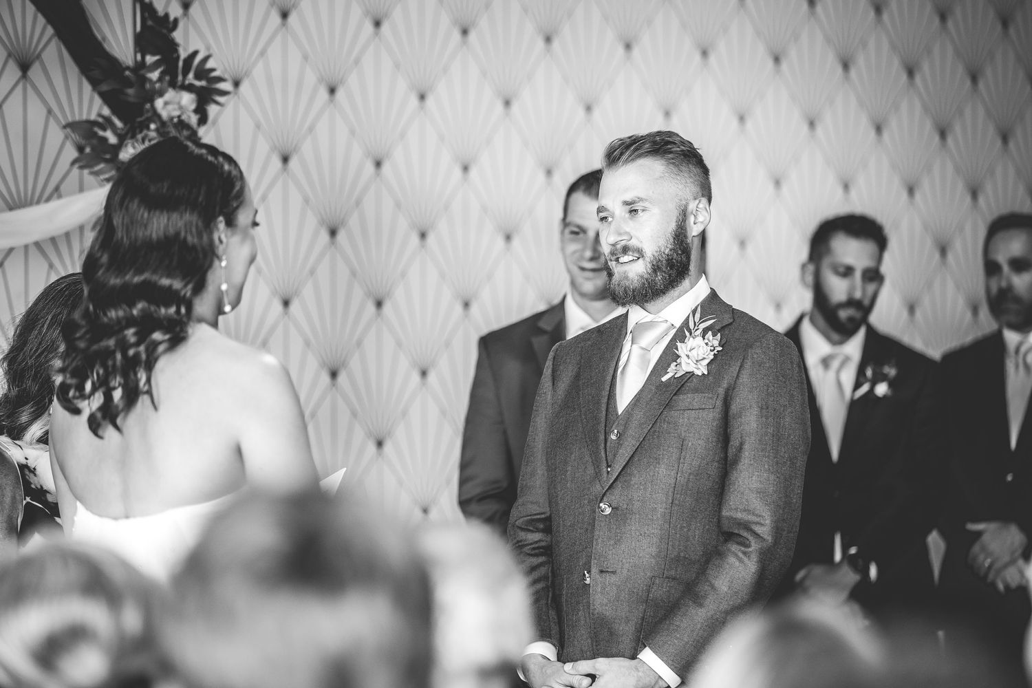 Wedding ceremony in progress under elegant art deco wallpaper.