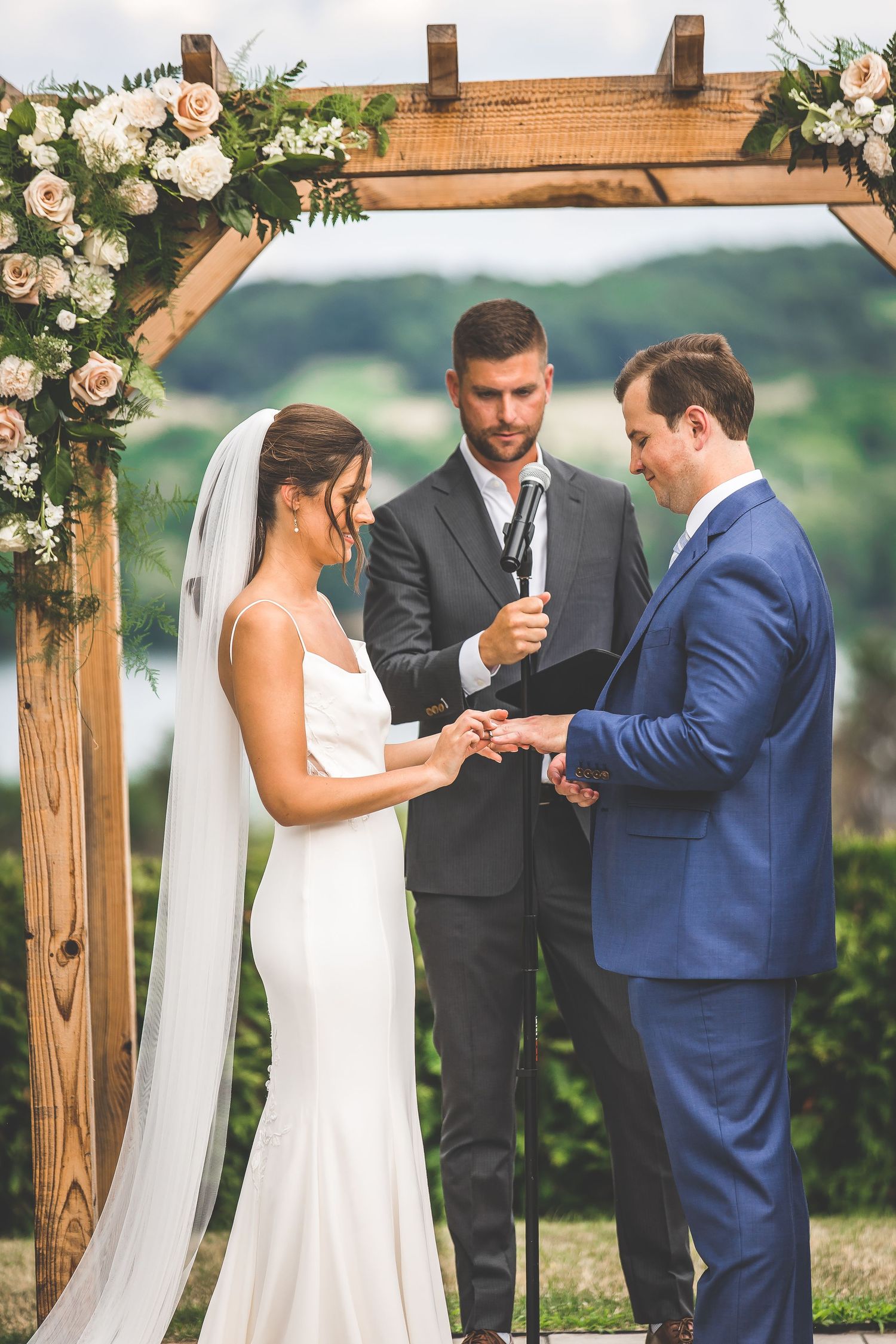 Wedding ceremony moments under rustic wooden arch decorated with white roses.