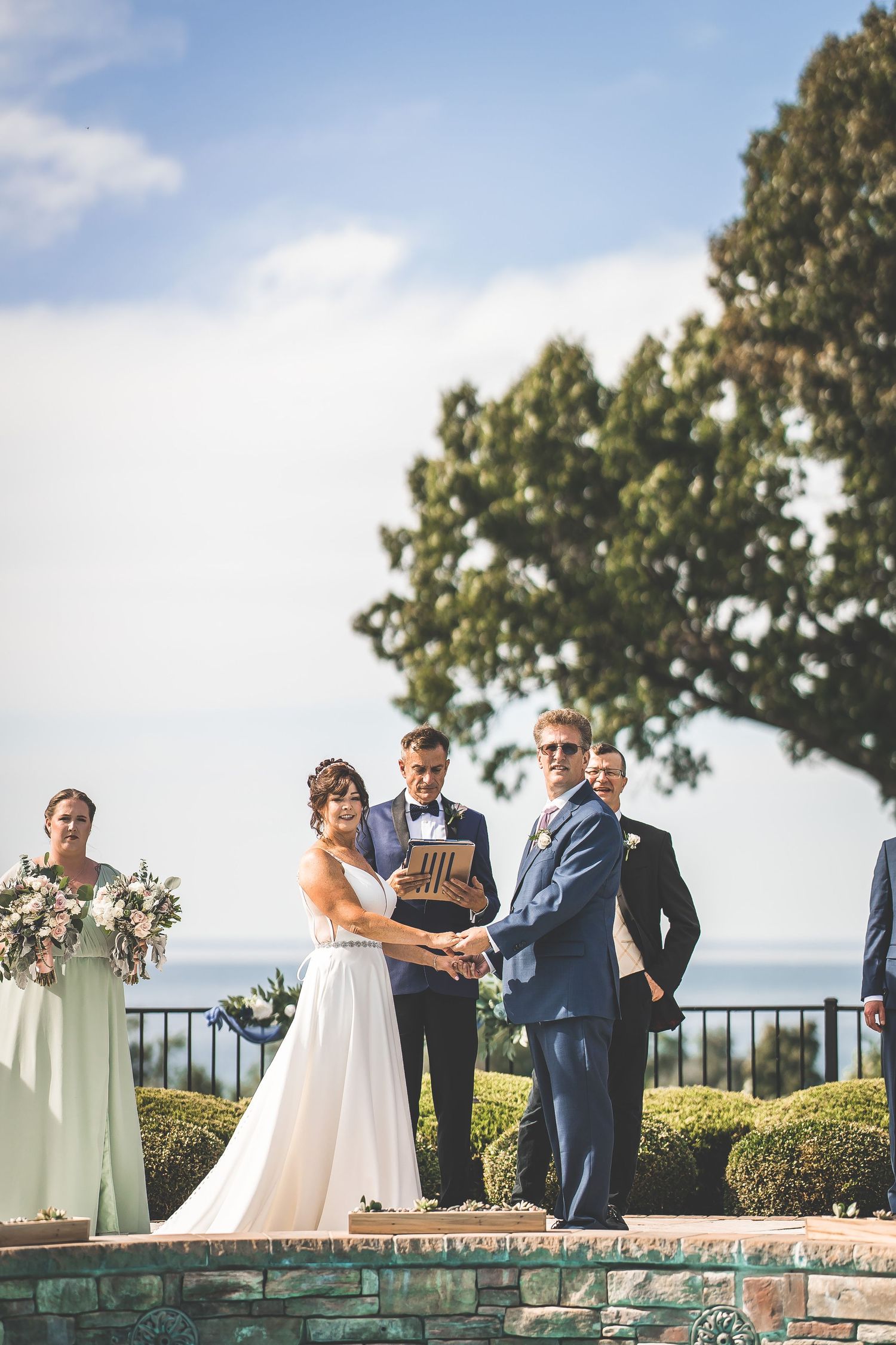 Outdoor wedding ceremony taking place on a terrace overlooking a scenic landscape.