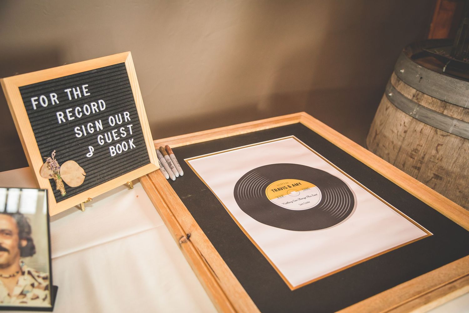 Wedding guest book table featuring a vintage record display and rustic wooden barrel decor.
