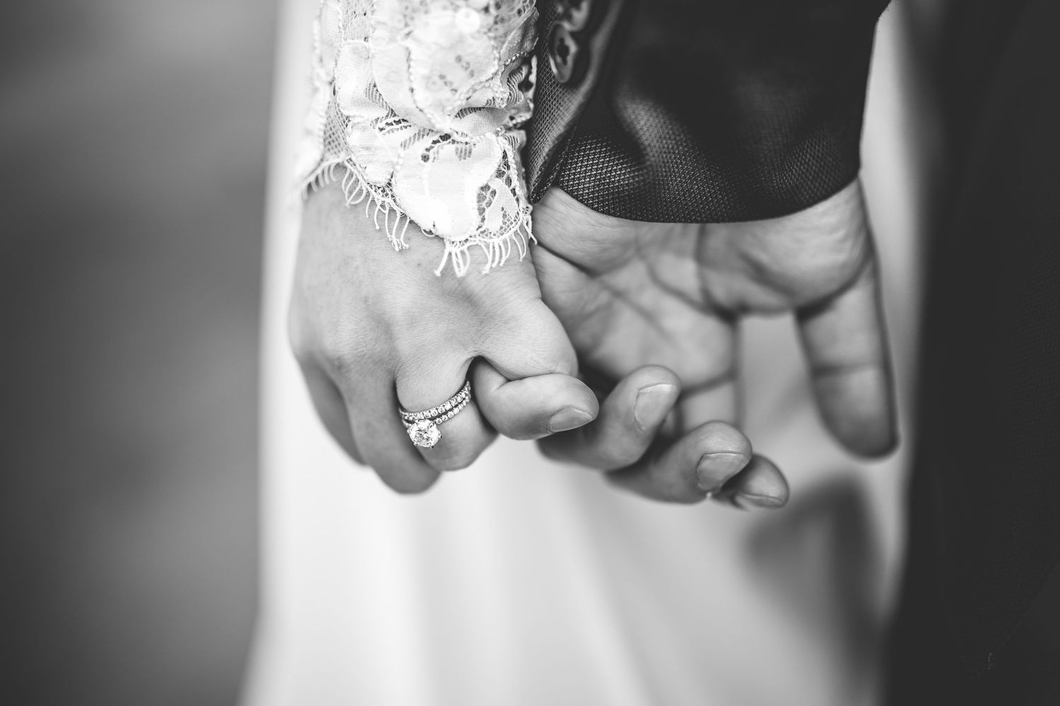 Black and white close-up shot of hands holding during a wedding ceremony.