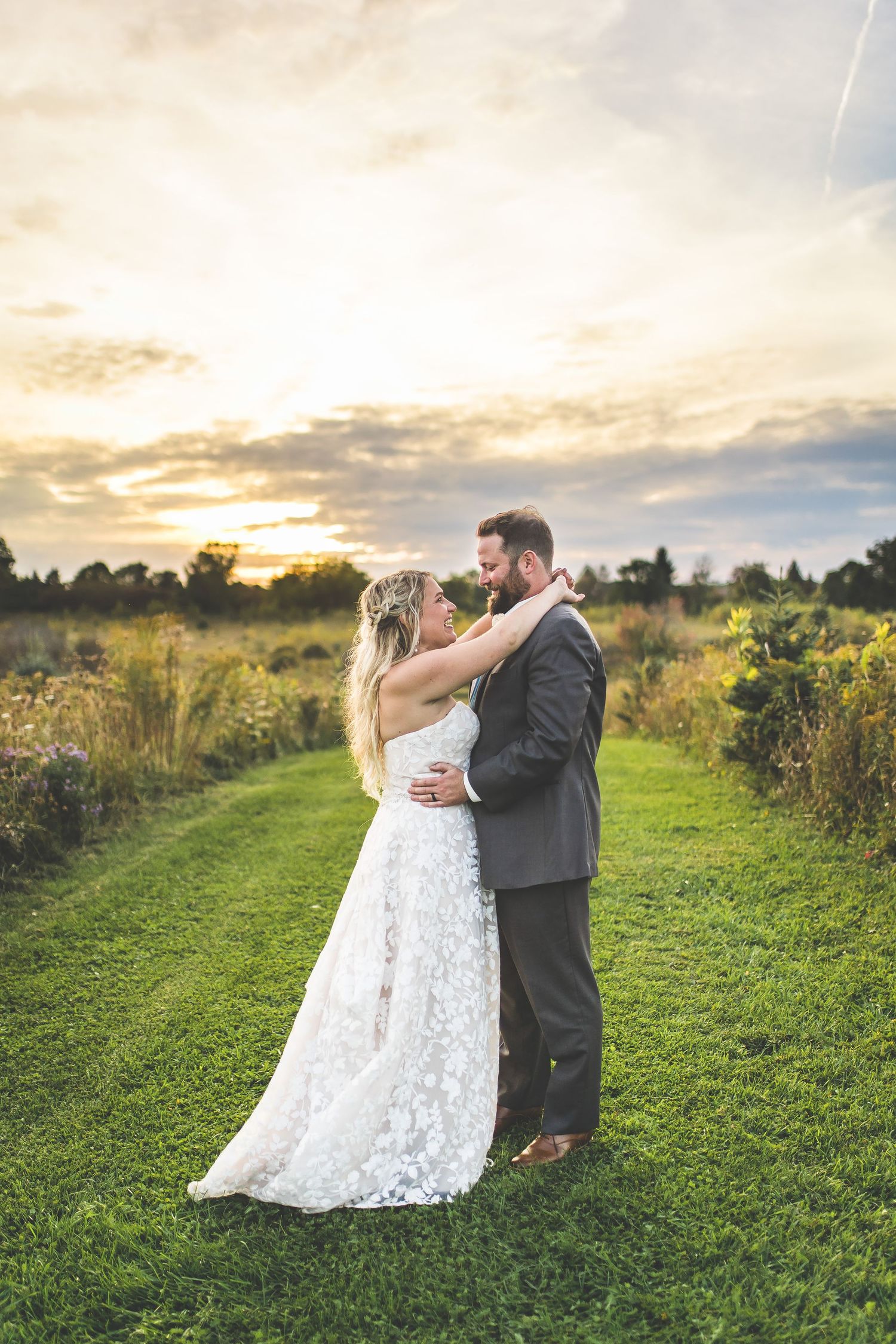 Couple dances together in golden hour light on grassy hillside path.