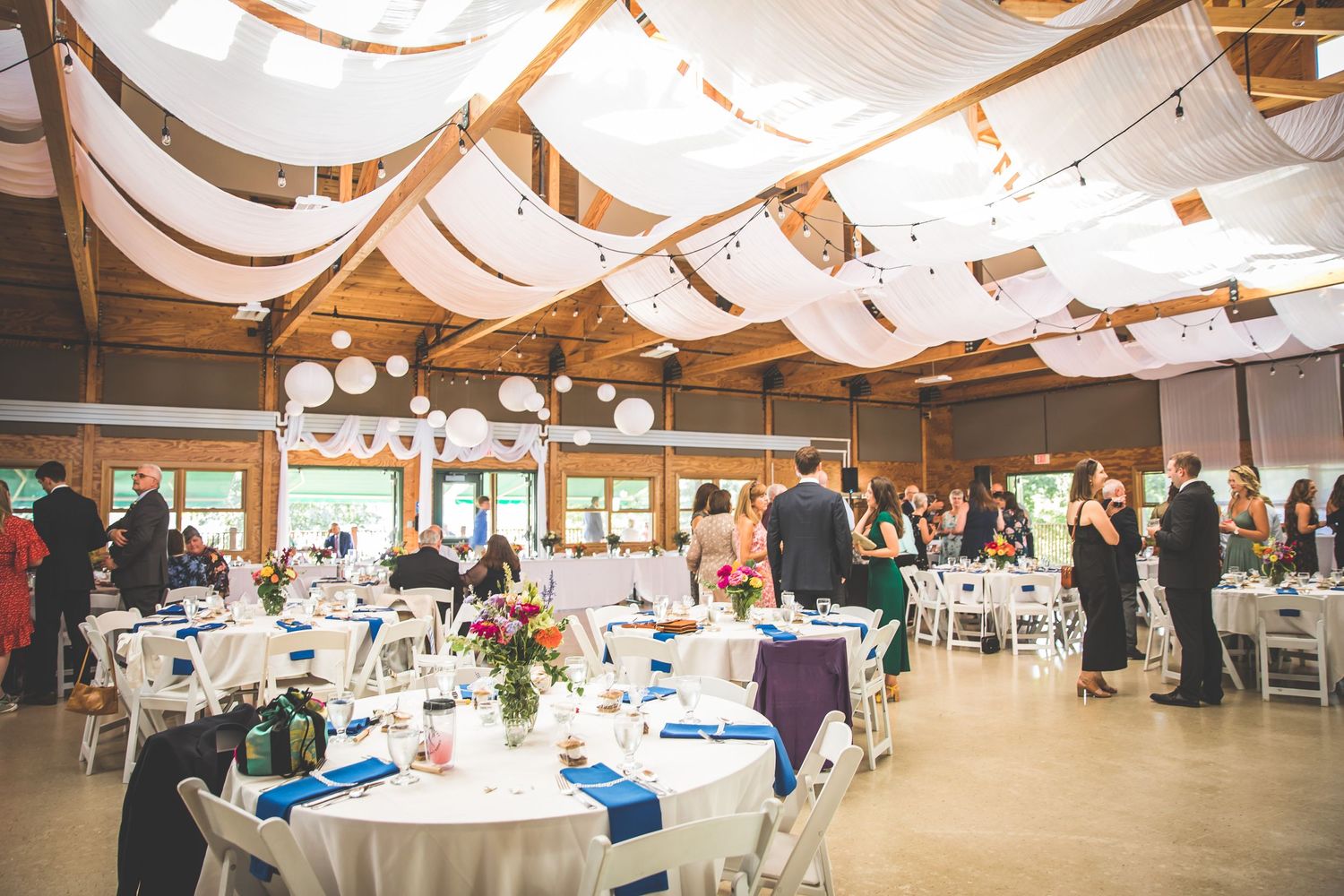 An elegant wedding reception venue with white draping and round tables set for dining.