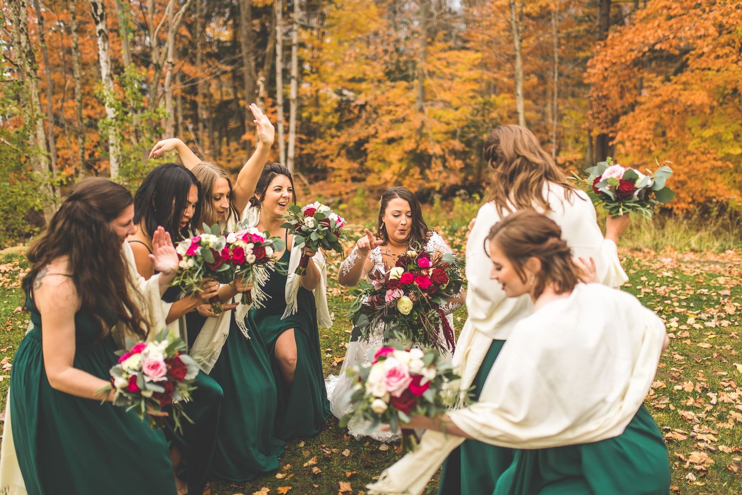 Wedding party celebrates in a wooded area with stunning fall colors.