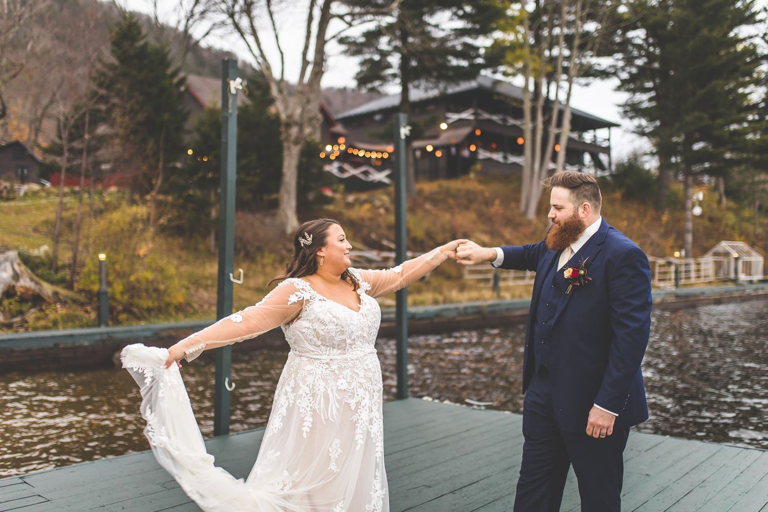 A couple shares a dance on a waterfront deck during their fall wedding celebration.