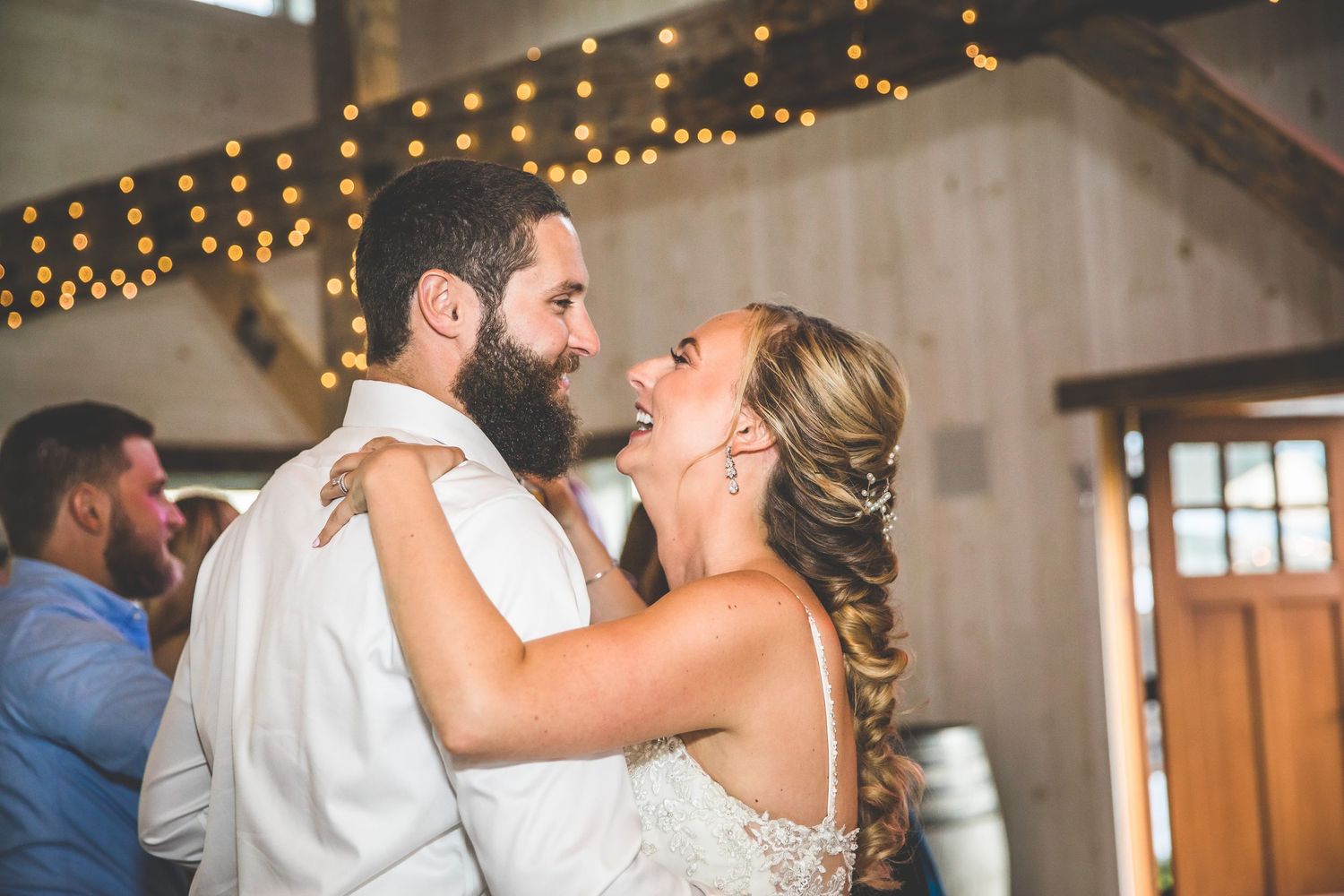 Wedding reception celebration with string lights decorating rustic wooden beams overhead.