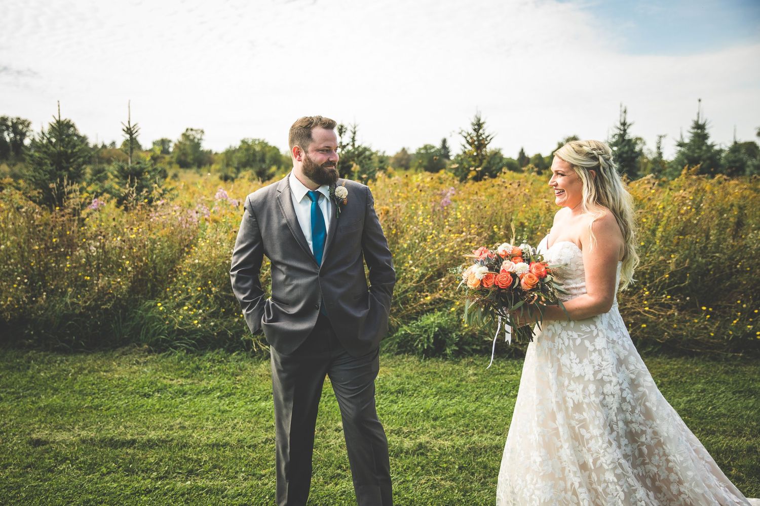 Newlyweds share an intimate moment in a sunlit meadow surrounded by lush greenery.