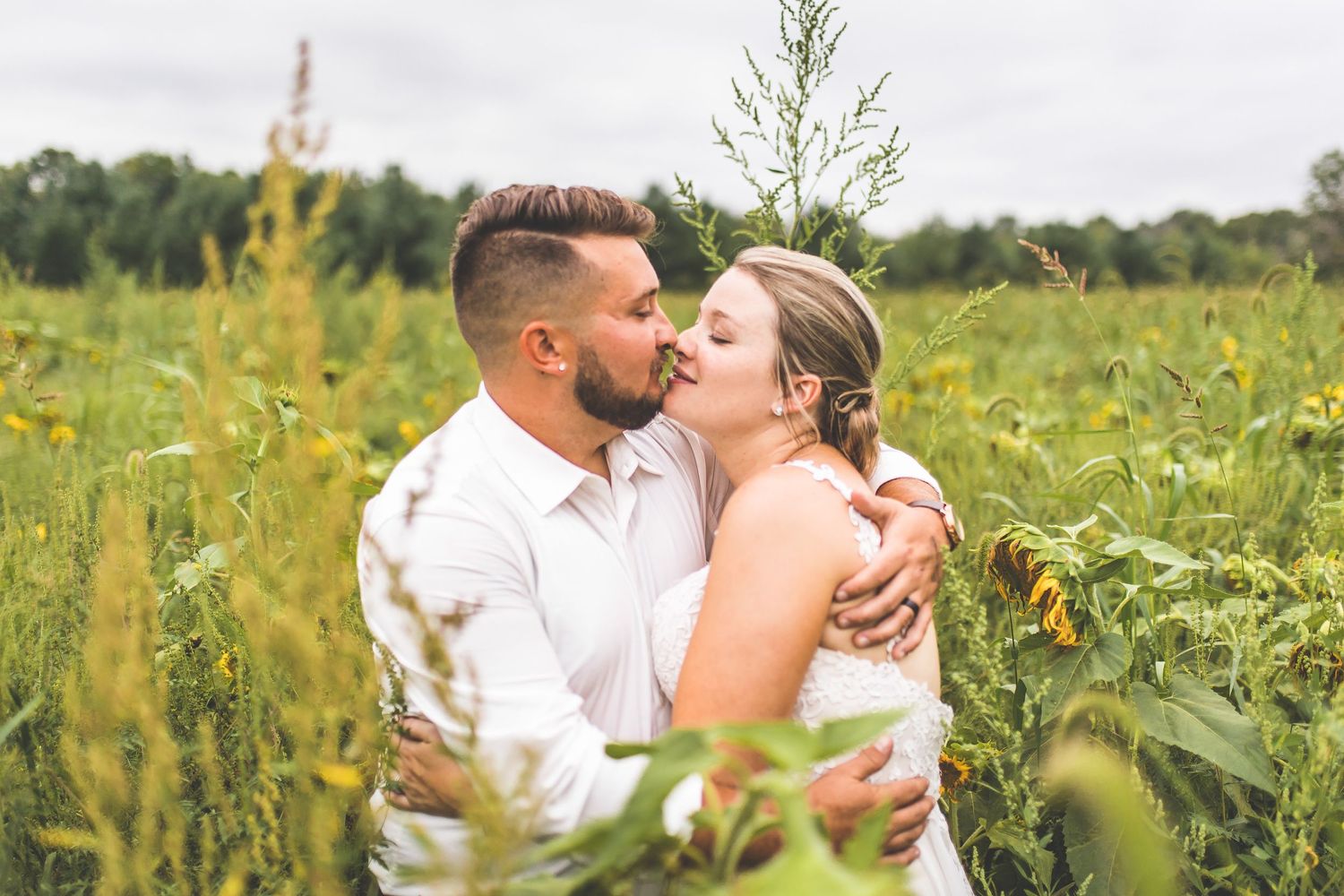 A romantic moment shared between a couple embracing in a wildflower meadow on a summer day.