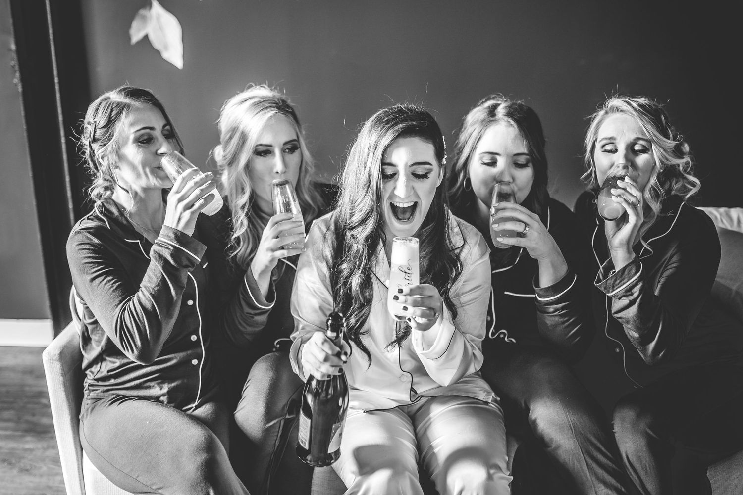 Black and white candid photo captures joyful reactions during wedding party celebrations.