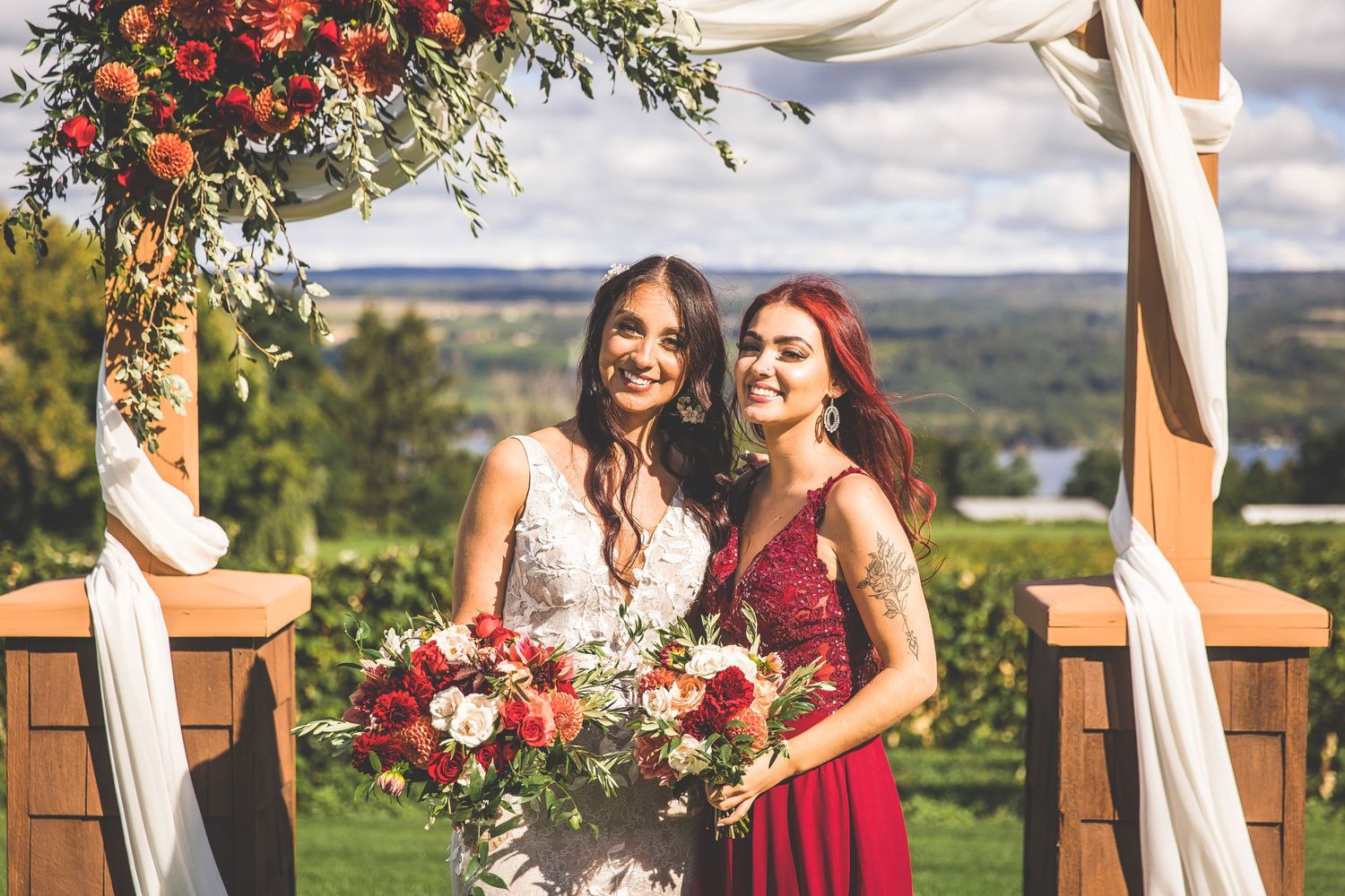 Wedding ceremony moment under a floral arch with red and white decorations.