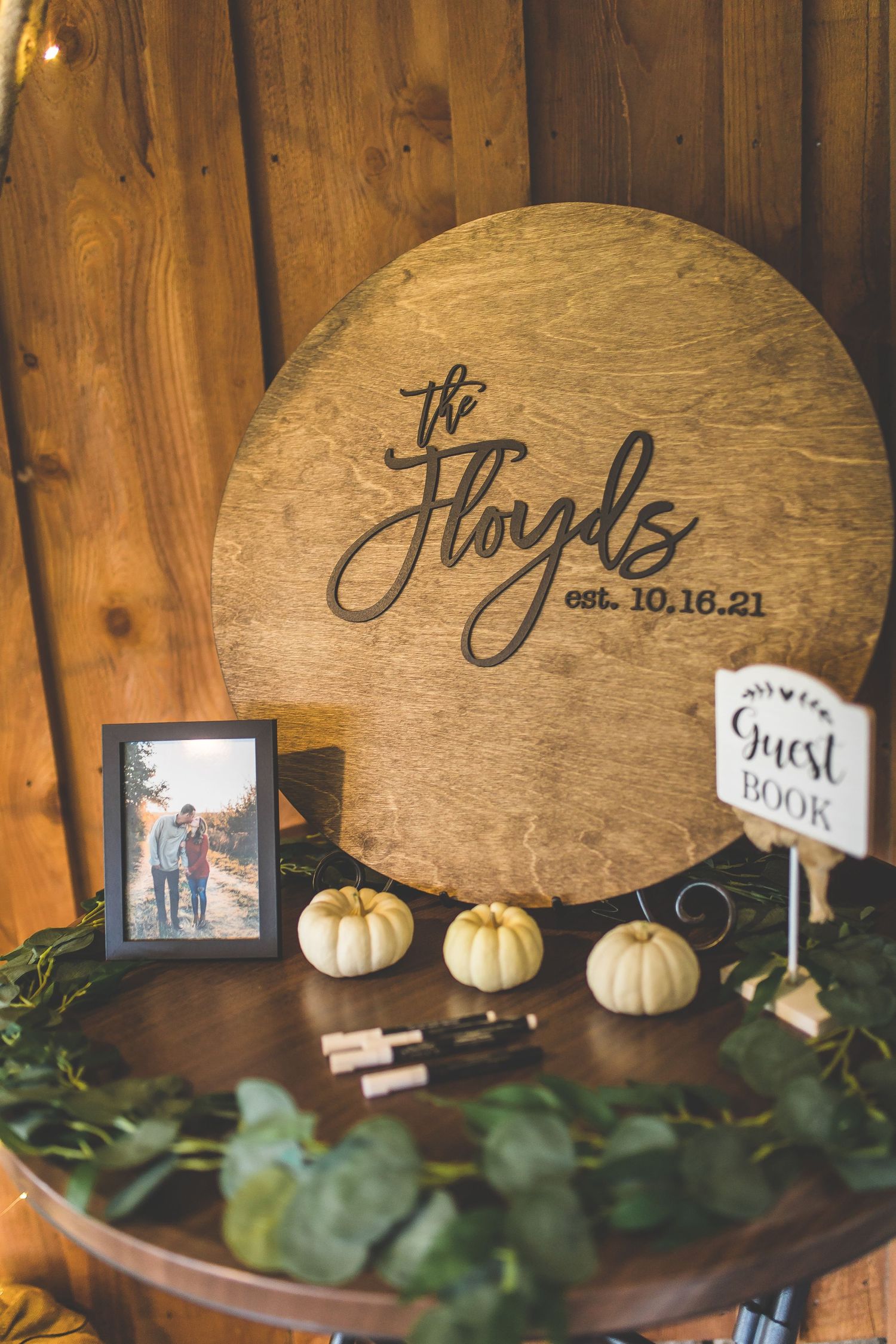 Rustic wooden signs with handwritten text and white pumpkins displayed at a fall wedding.