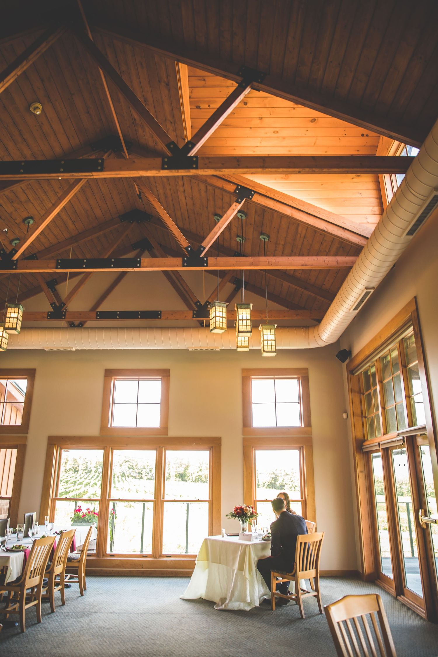 Rustic wedding venue interior featuring exposed wooden beams and large windows.
