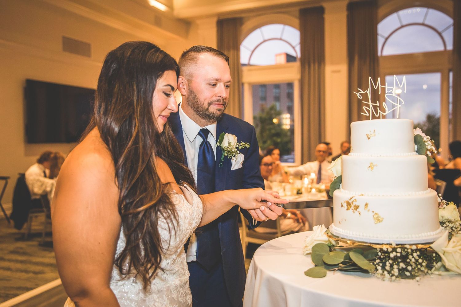 Wedding reception venue with elegant table settings and tiered cake display.