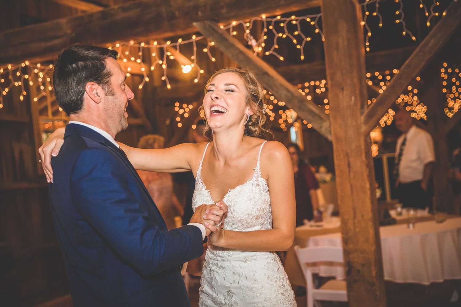 Romantic first dance in a barn venue with twinkling fairy lights.