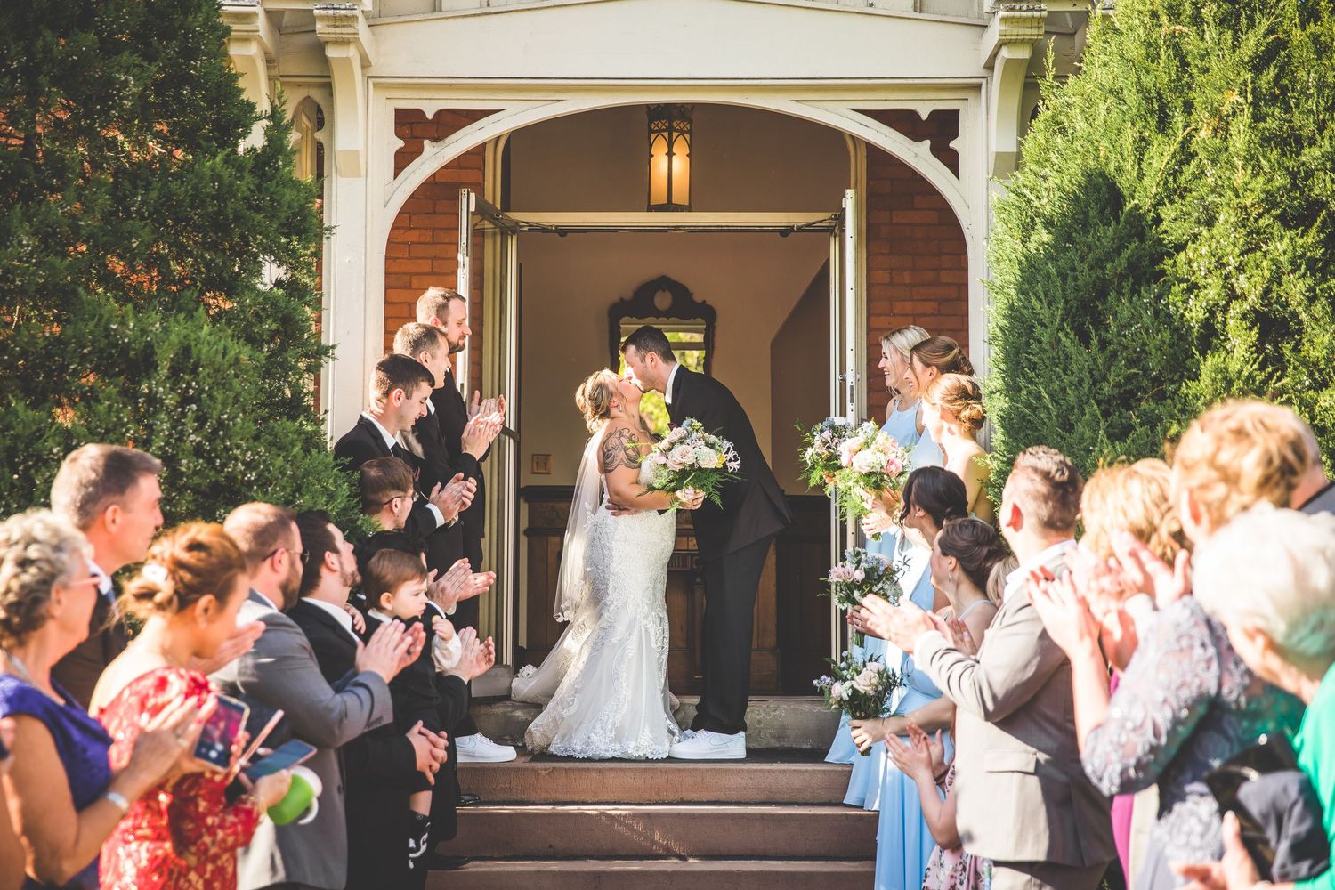 Wedding party and guests gathered outside a church entrance for post-ceremony celebrations.