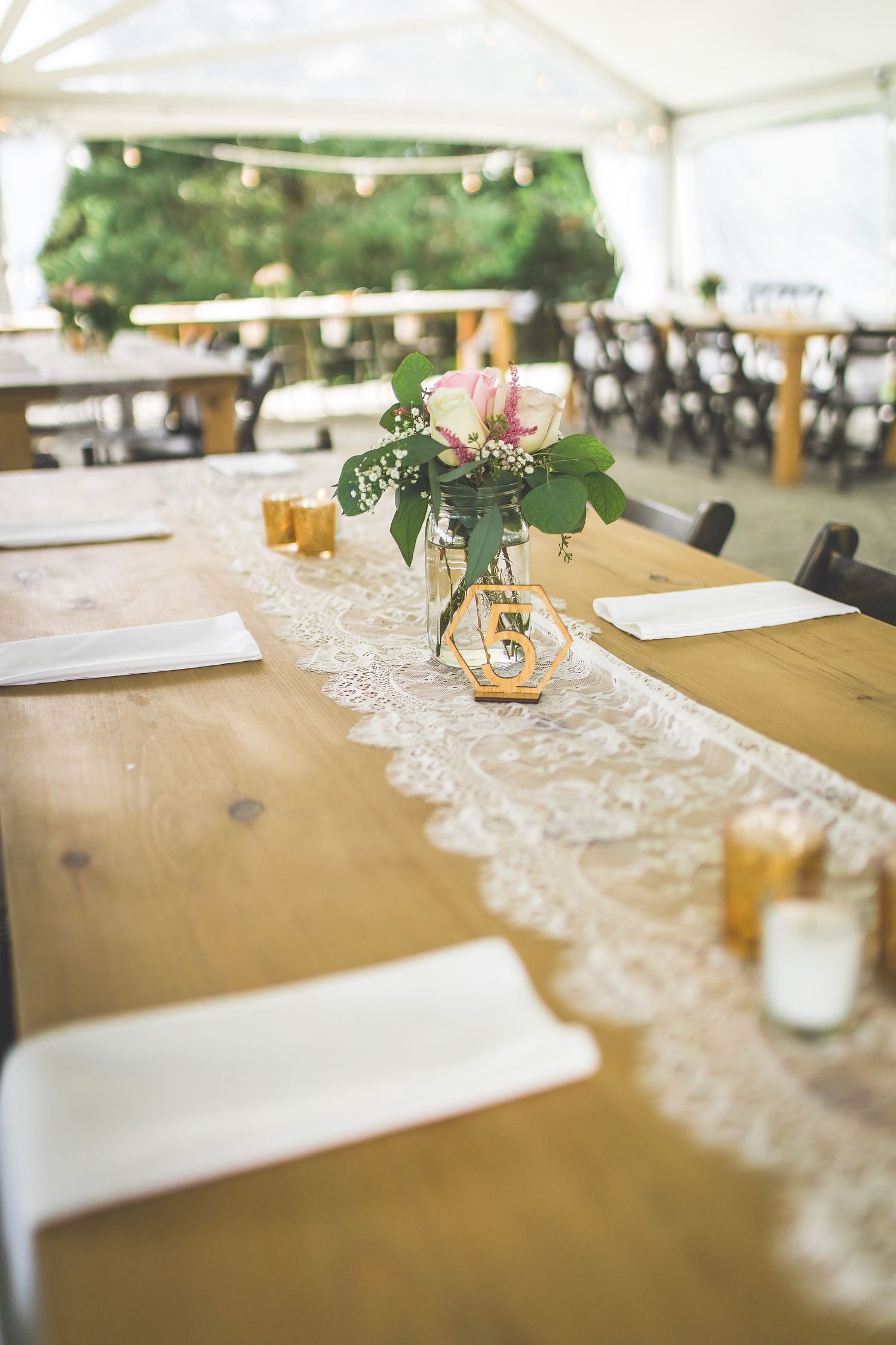 Elegant wedding reception table settings with lace runners and gold accents.