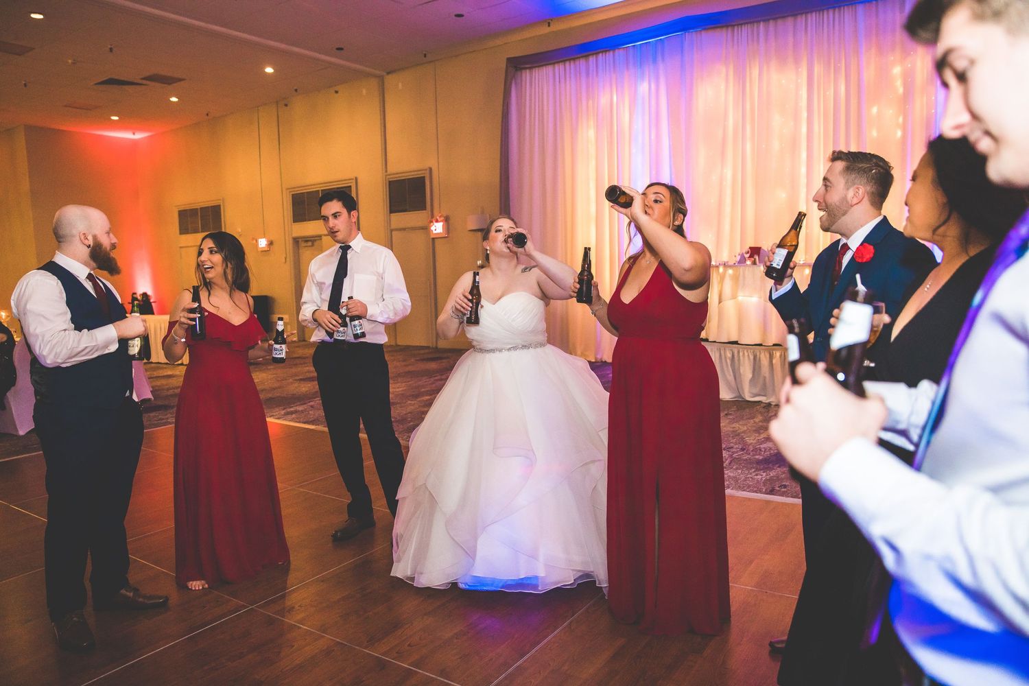 Wedding reception dance party with dramatic purple and blue lighting effects on dance floor.