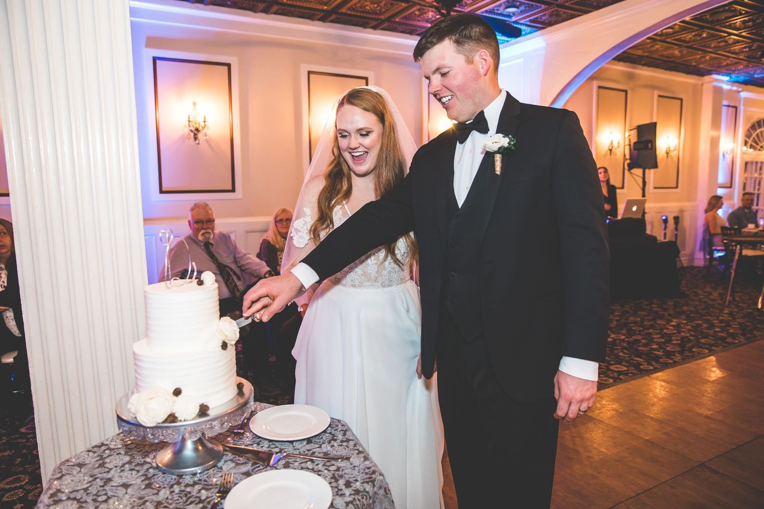 Wedding celebration in a luxurious ballroom with blue accent lighting and ornate decor.