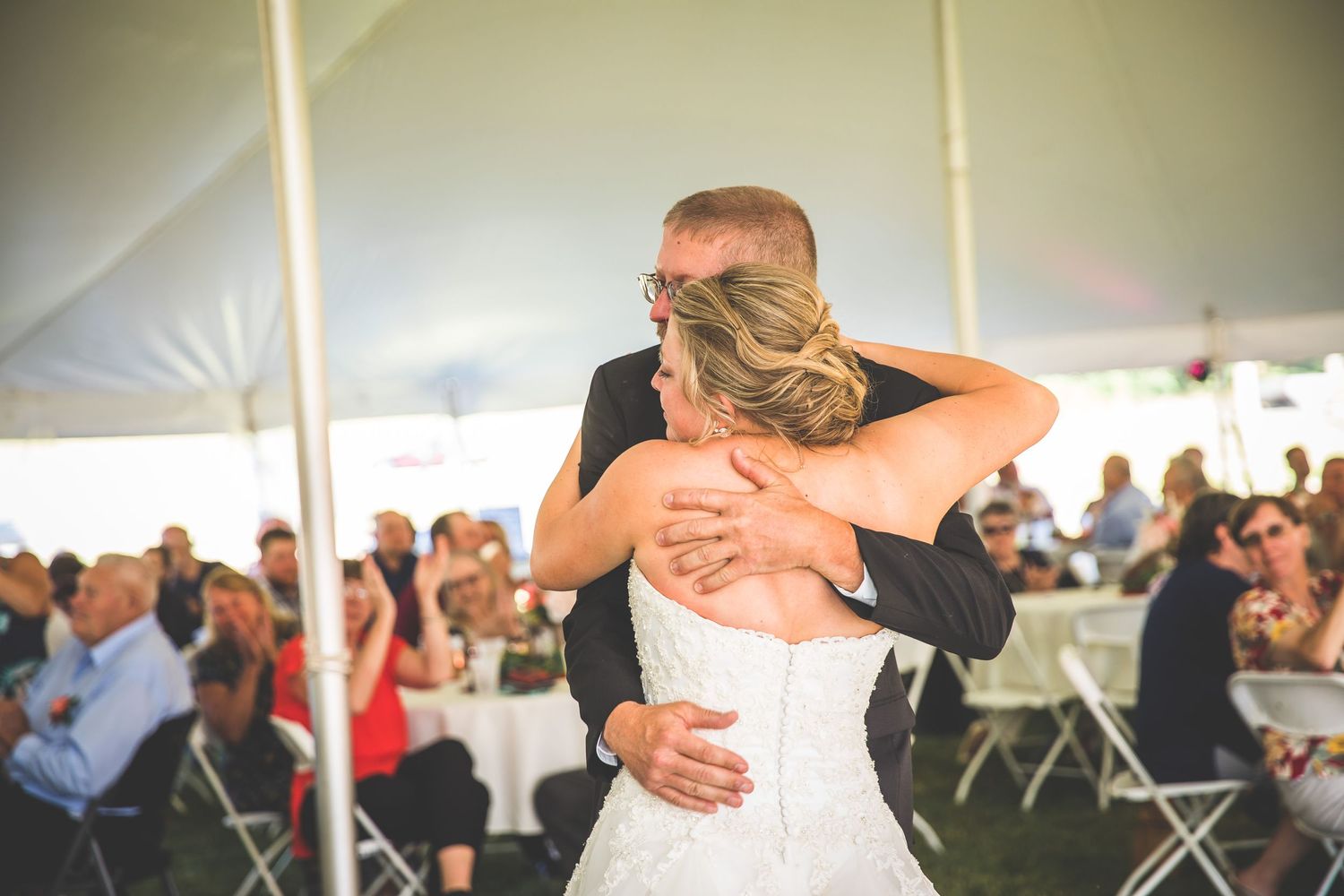 Couple shares a tender embrace while dancing at their outdoor wedding reception.