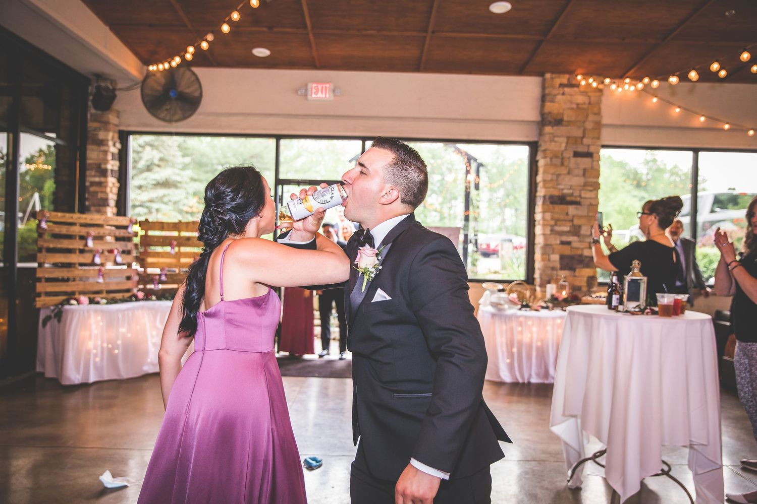 Reception venue with string lights and round tables set for wedding celebration.