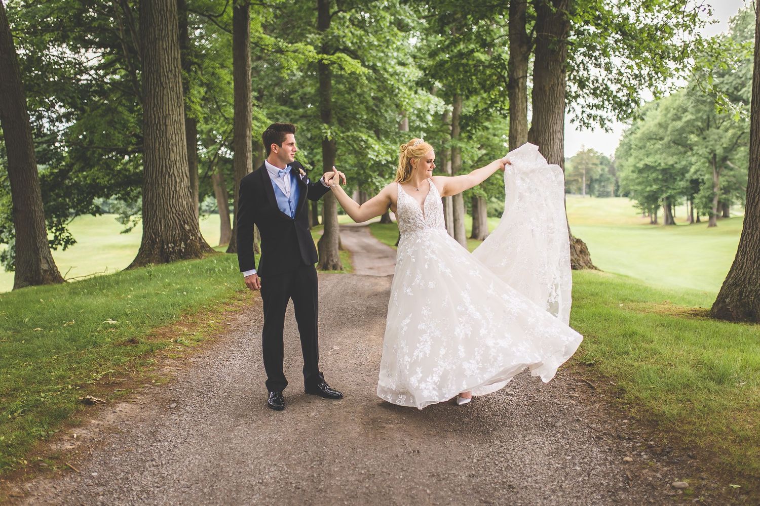 Couple poses playfully on a garden path as the bride's dress flows in the breeze.