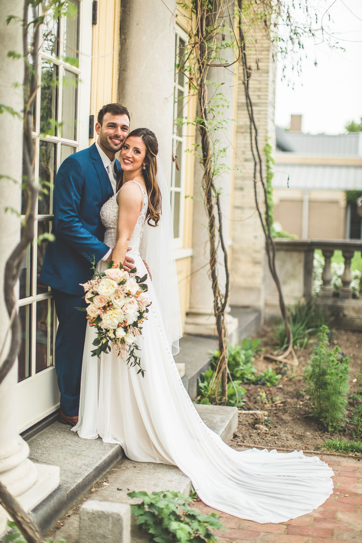 Elegant wedding portraits against stone building with climbing vines.