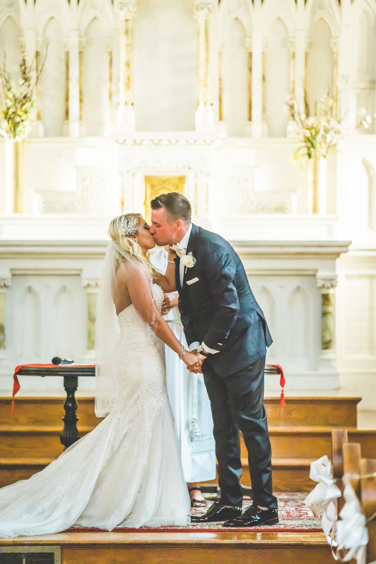 Wedding ceremony in ornate white church interior with gothic architectural details.