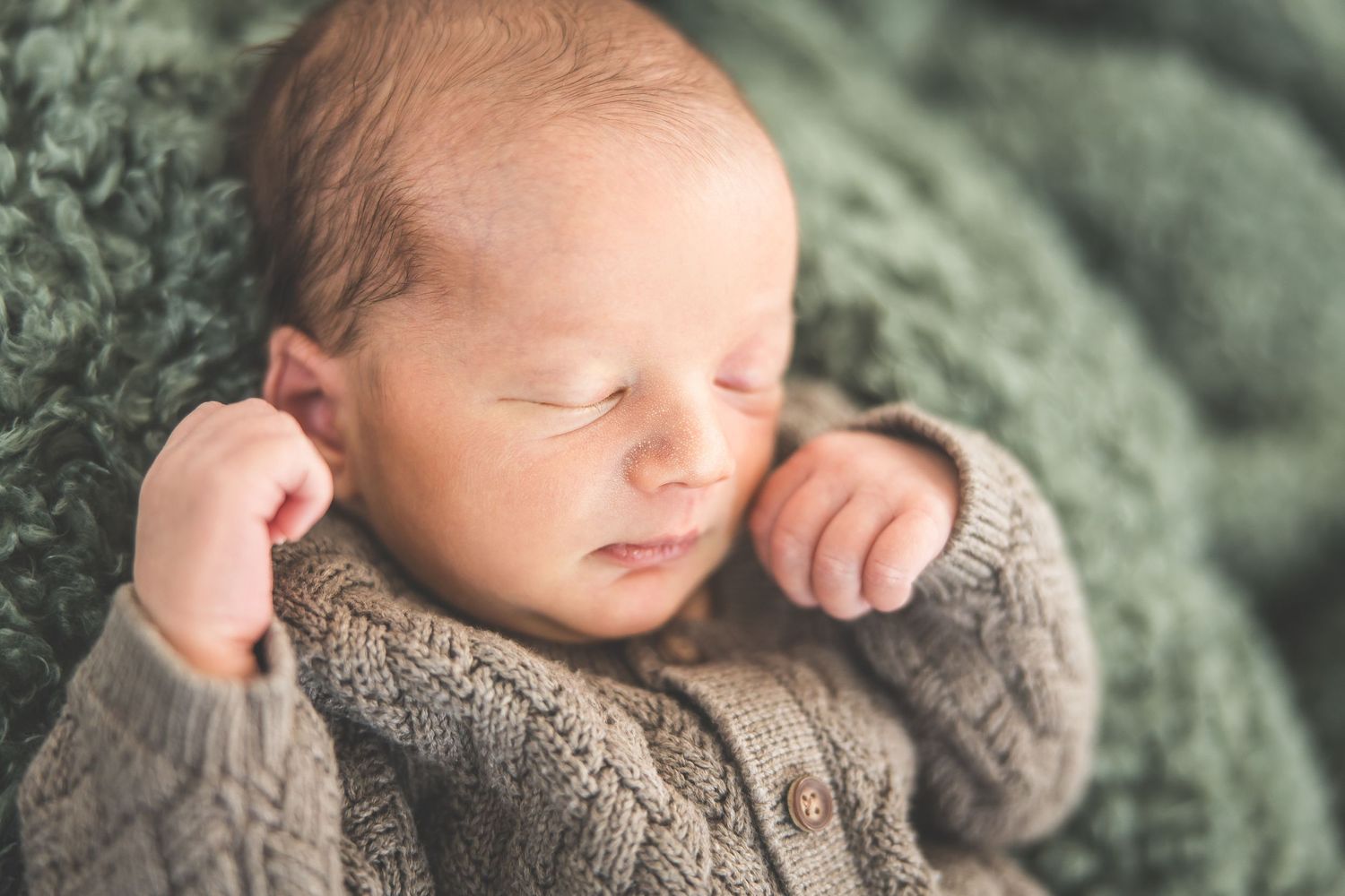 A sleeping baby wrapped in a cozy gray knit blanket.