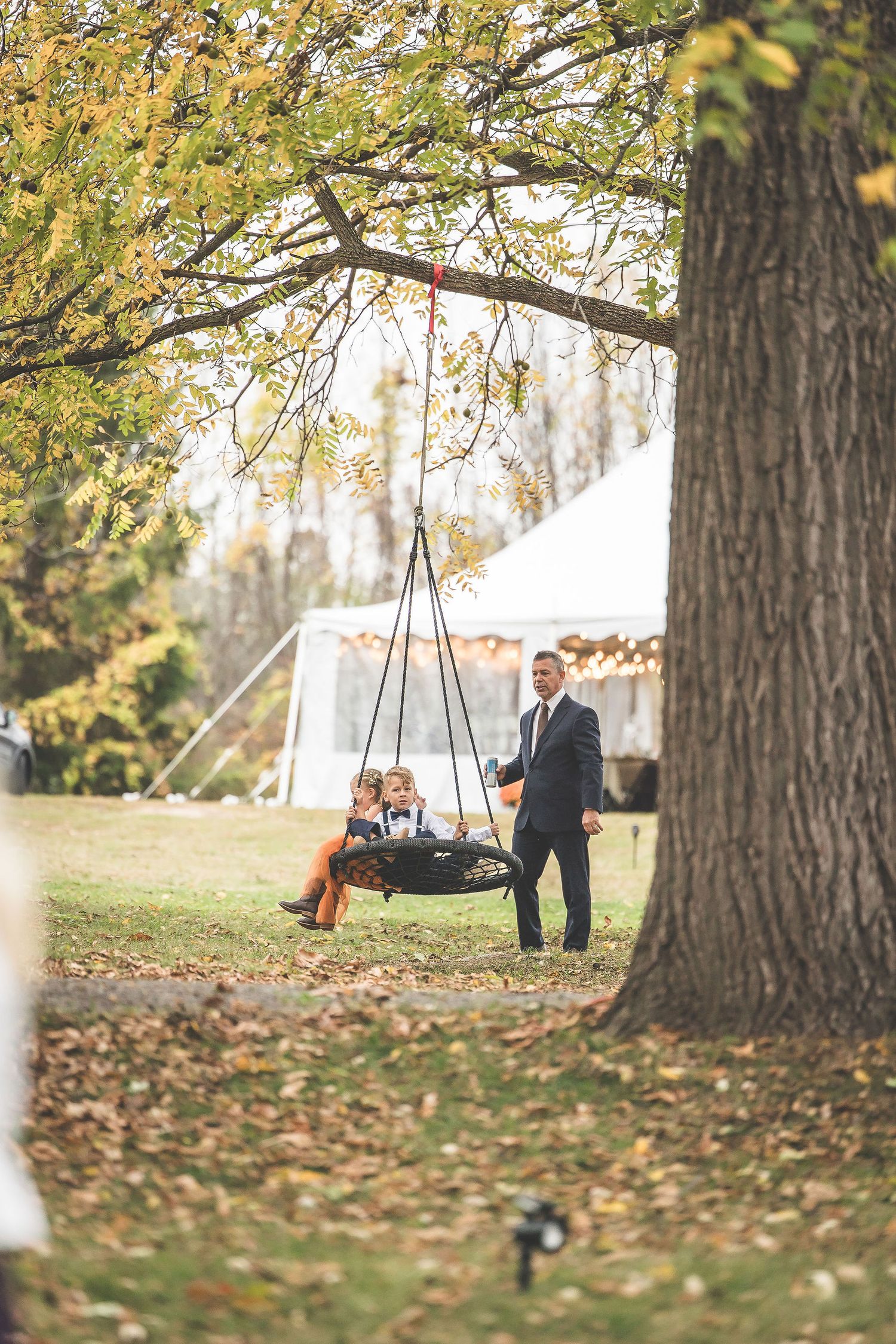 Tree swing photo session during an autumn wedding with fallen leaves.