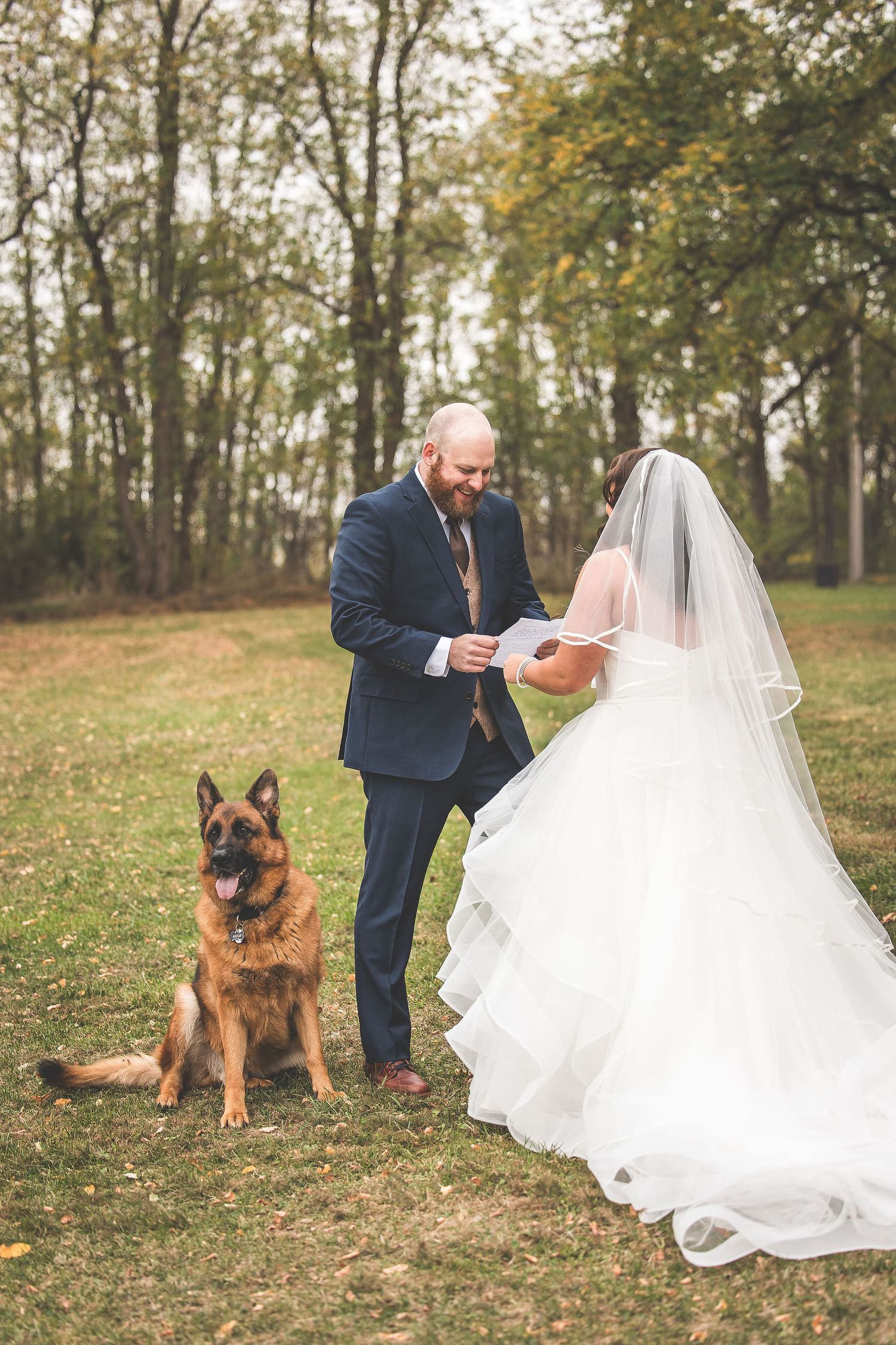 A couple reads their vows while their German Shepherd sits attentively beside them.