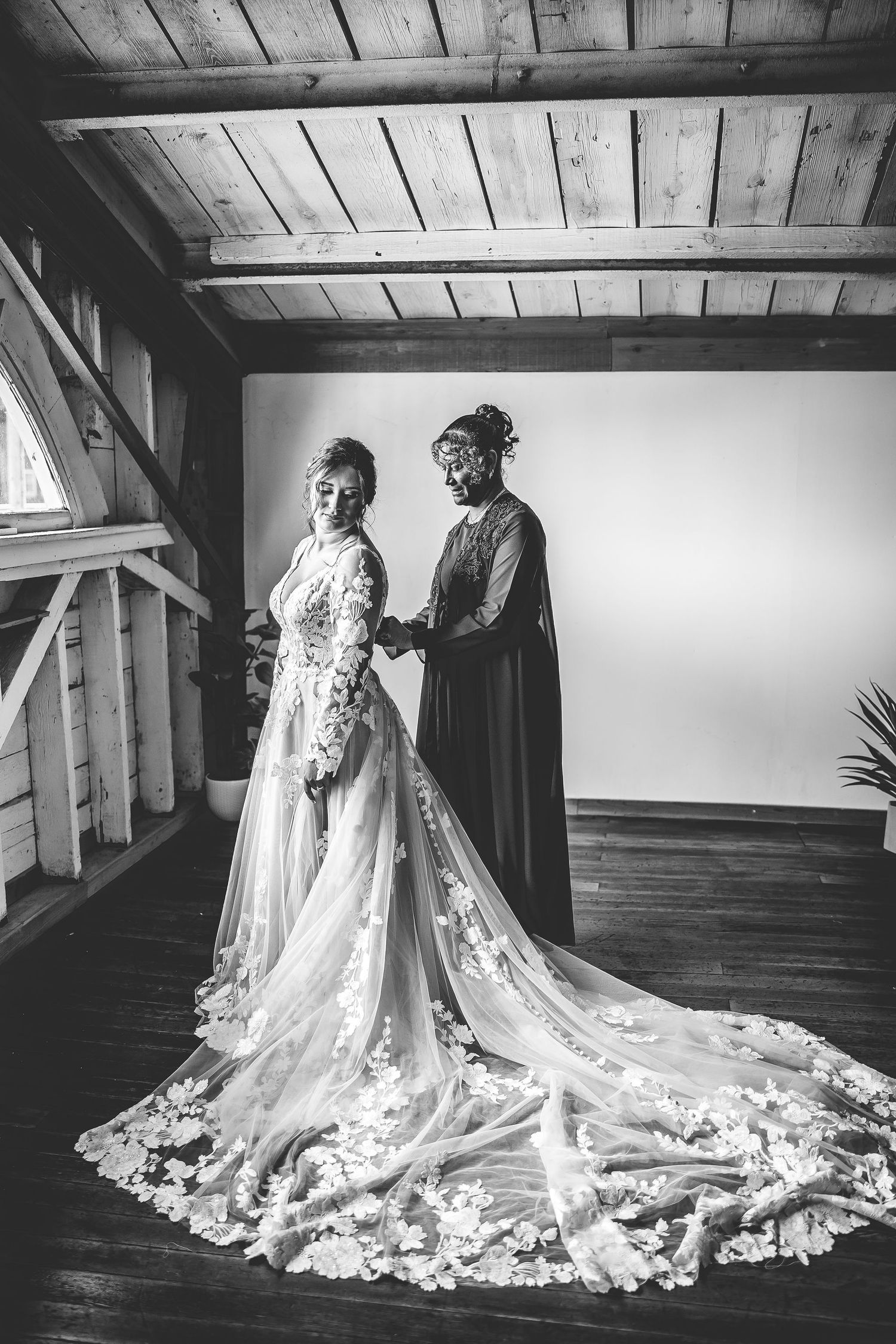 Black and white photo showcasing intricate lace wedding dress with dramatic train.