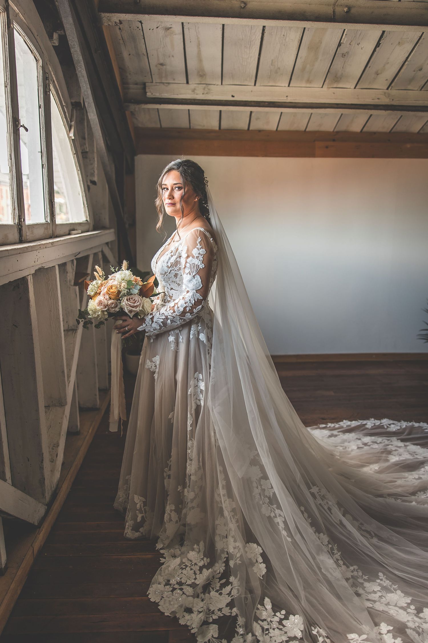 Romantic bridal portrait series in rustic attic venue with dramatic cathedral length veil.