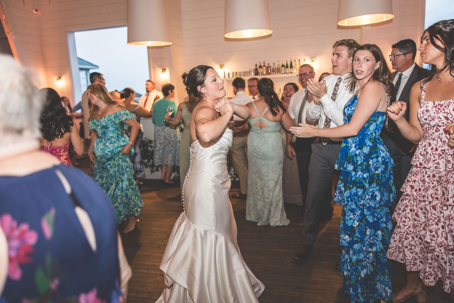 Wedding reception dance floor filled with guests in colorful attire enjoying the celebration.