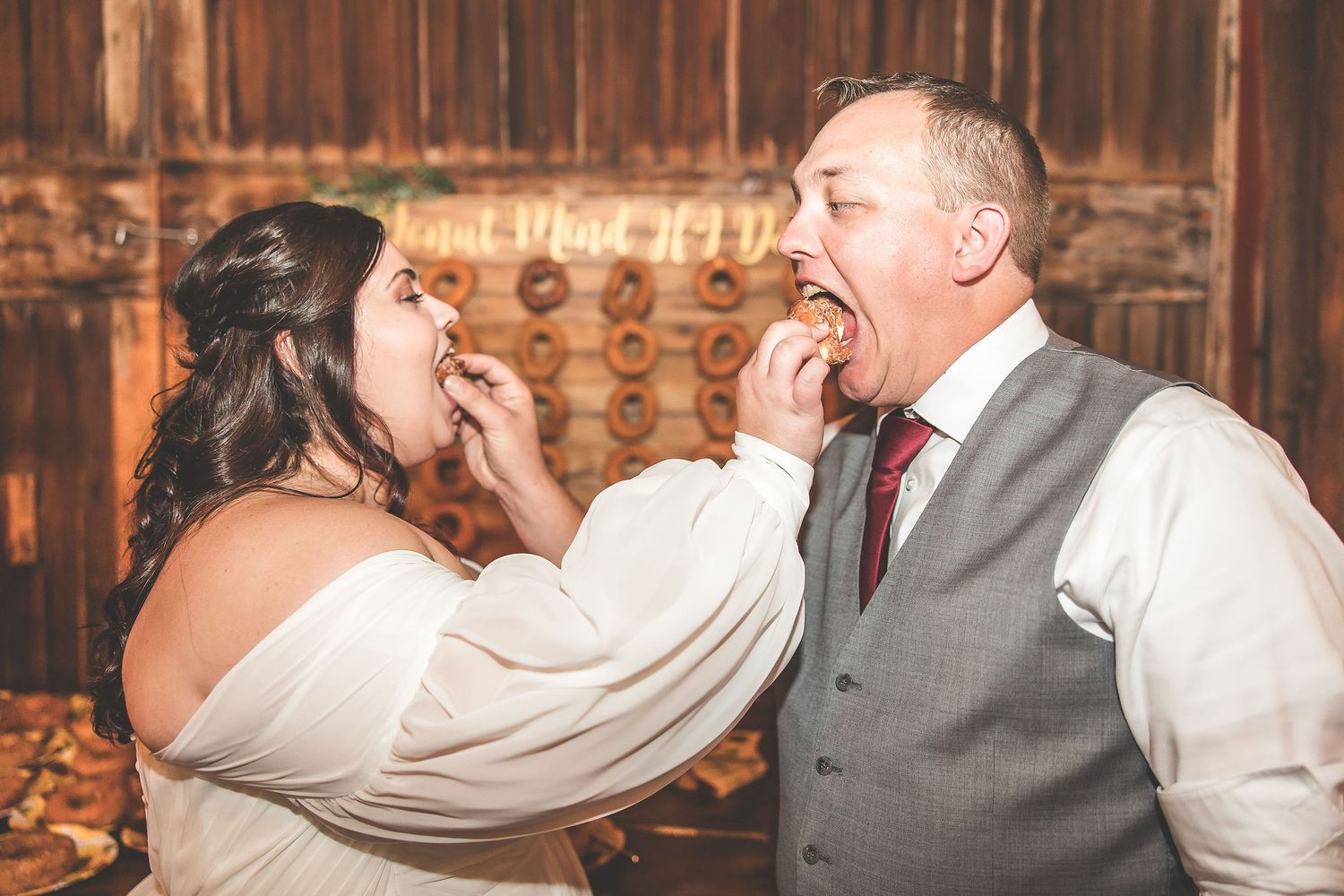 Playful moment as couple feeds each other donuts at their wedding reception.