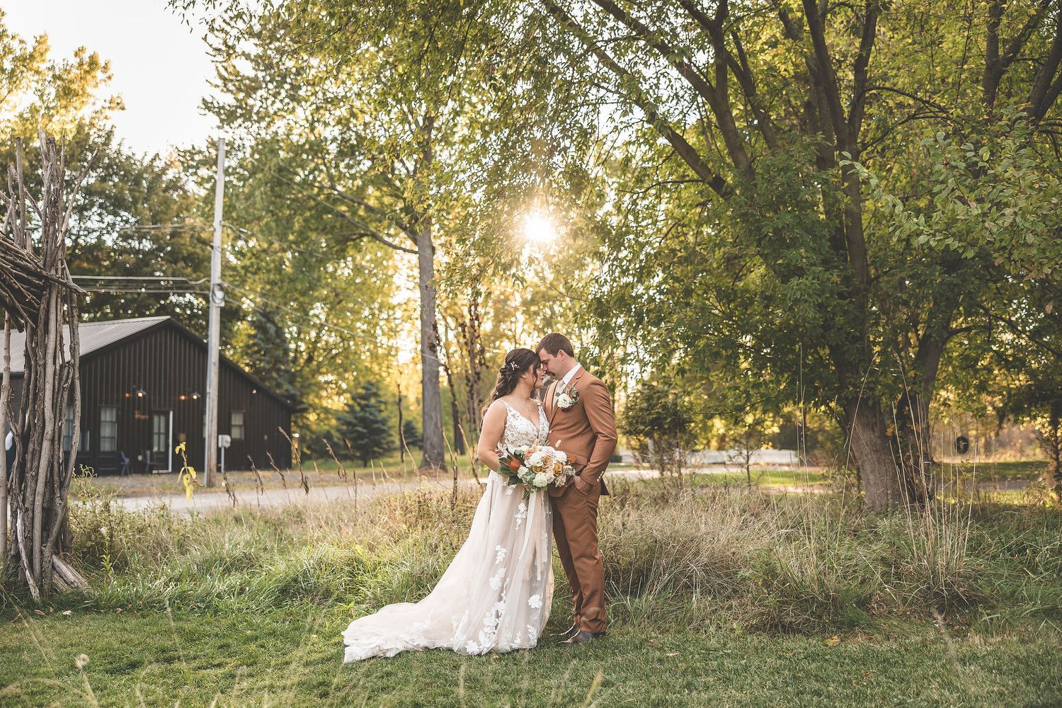 Wedding couple strolls through a scenic autumn landscape with golden sunlight filtering through trees.